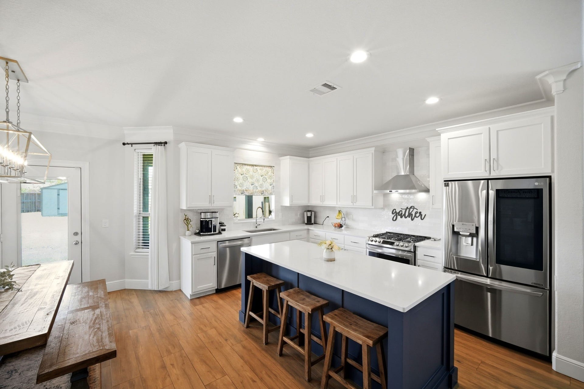 21639 Lexor Drive, Porter, TX 77365 Spacious kitchen featuring a large island with seating, stainless steel appliances, and elegant white cabinetry, complemented by warm flooring and abundant natural light.