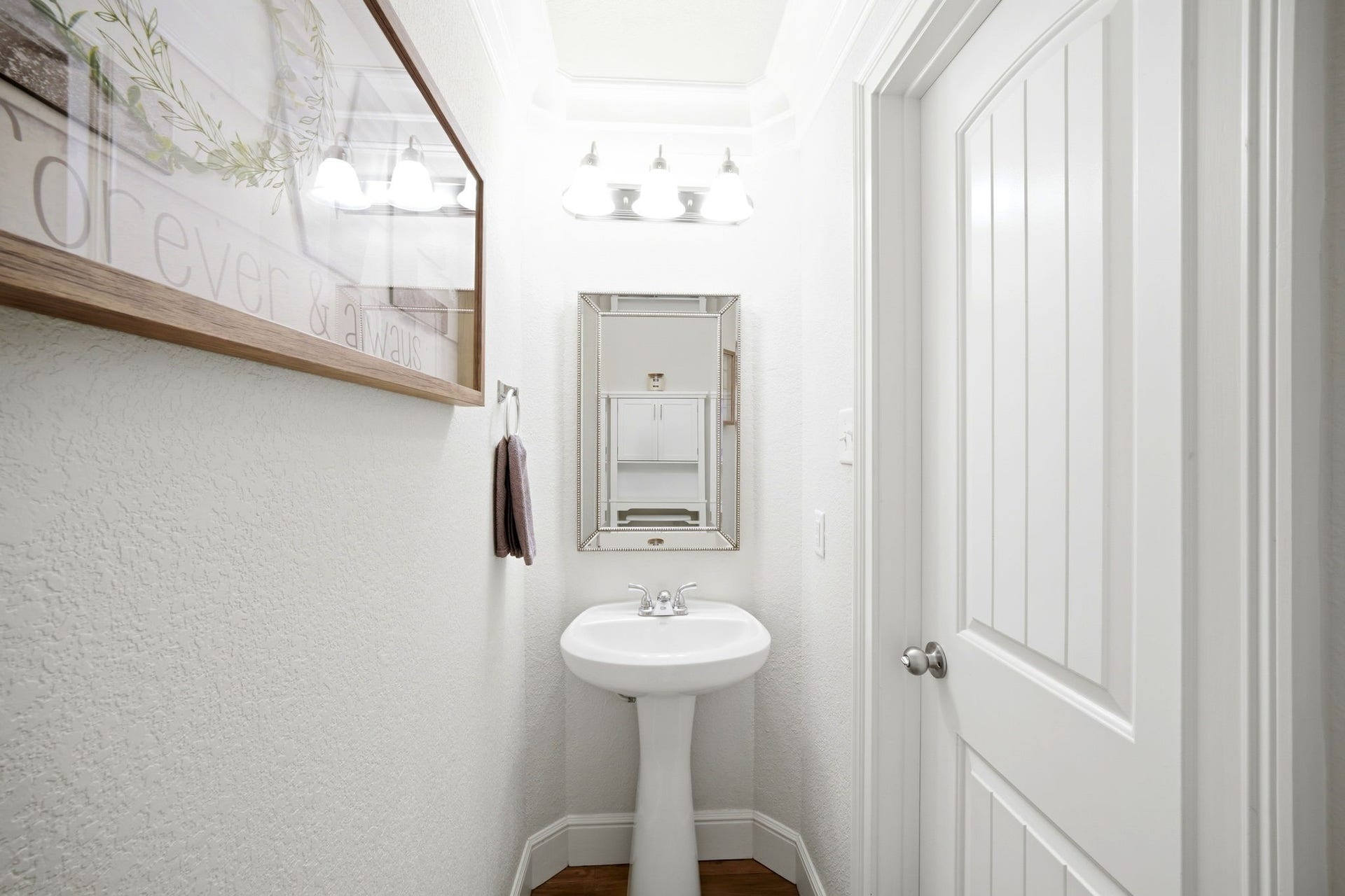 21639 Lexor Drive, Porter, TX 77365 Charming powder room with a sleek pedestal sink, elegant mirror, and soft overhead lighting, offering a cozy and inviting space.