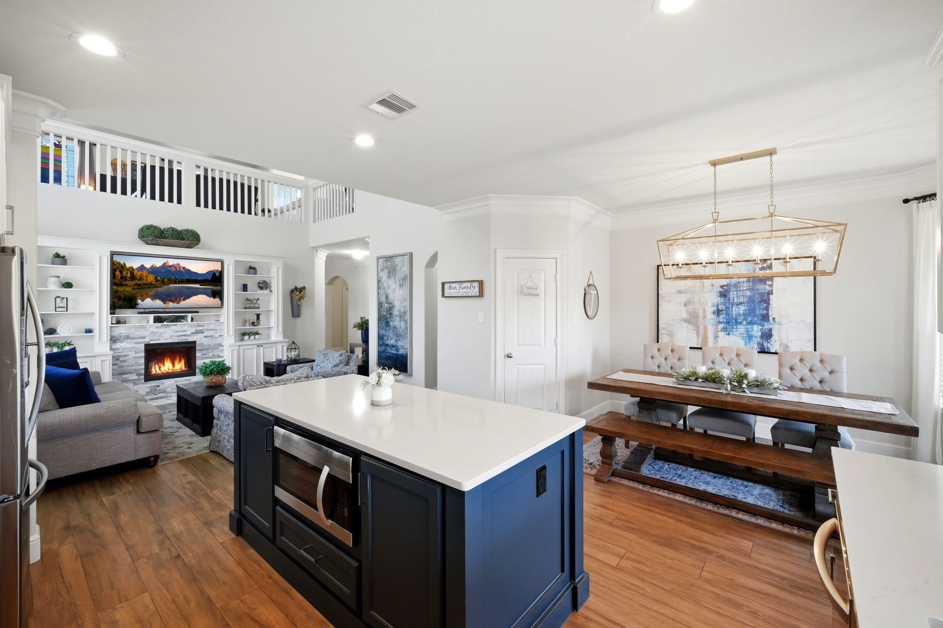 21639 Lexor Drive, Porter, TX 77365 Elegant open-concept living space featuring a cozy fireplace, modern kitchen island, and a stylish dining area with a statement light fixture.