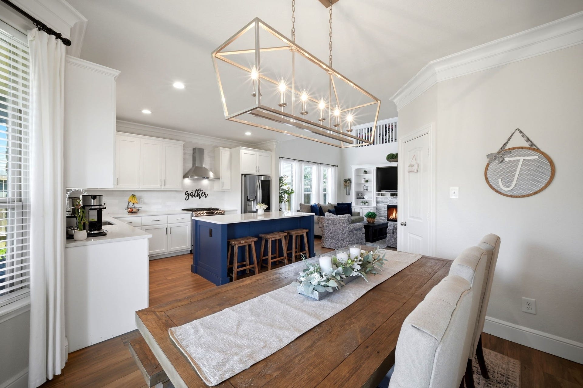 21639 Lexor Drive, Porter, TX 77365 Bright and inviting open-concept kitchen and dining area featuring a large island with seating, elegant light fixture, and cozy living space with a fireplace, perfect for gatherings.