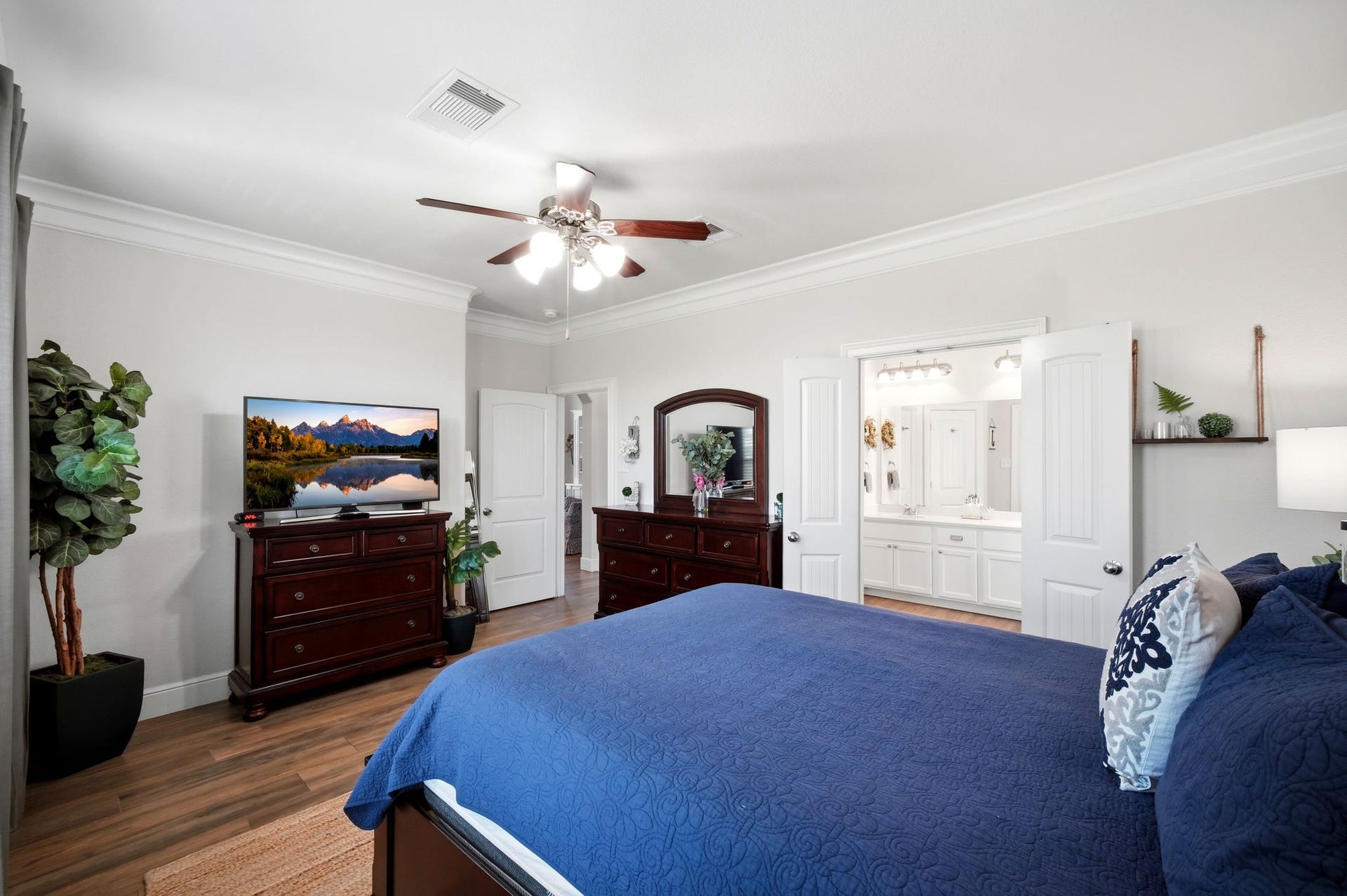 21639 Lexor Drive, Porter, TX 77365 Spacious bedroom with elegant flooring, a ceiling fan, and stylish furniture. The room opens to a bright en-suite bathroom with double doors.