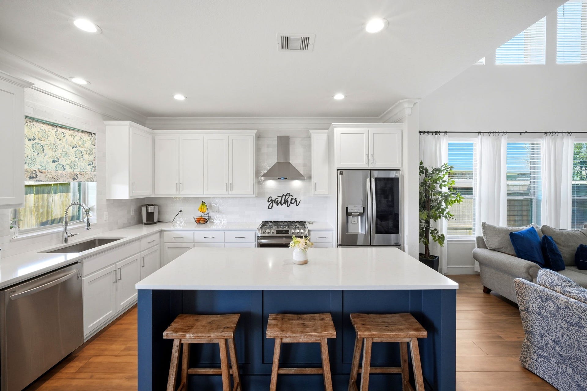 21639 Lexor Drive, Porter, TX 77365 Bright and spacious kitchen with sleek white cabinetry, a central island with seating, and stainless steel appliances, seamlessly flowing into an inviting living area.