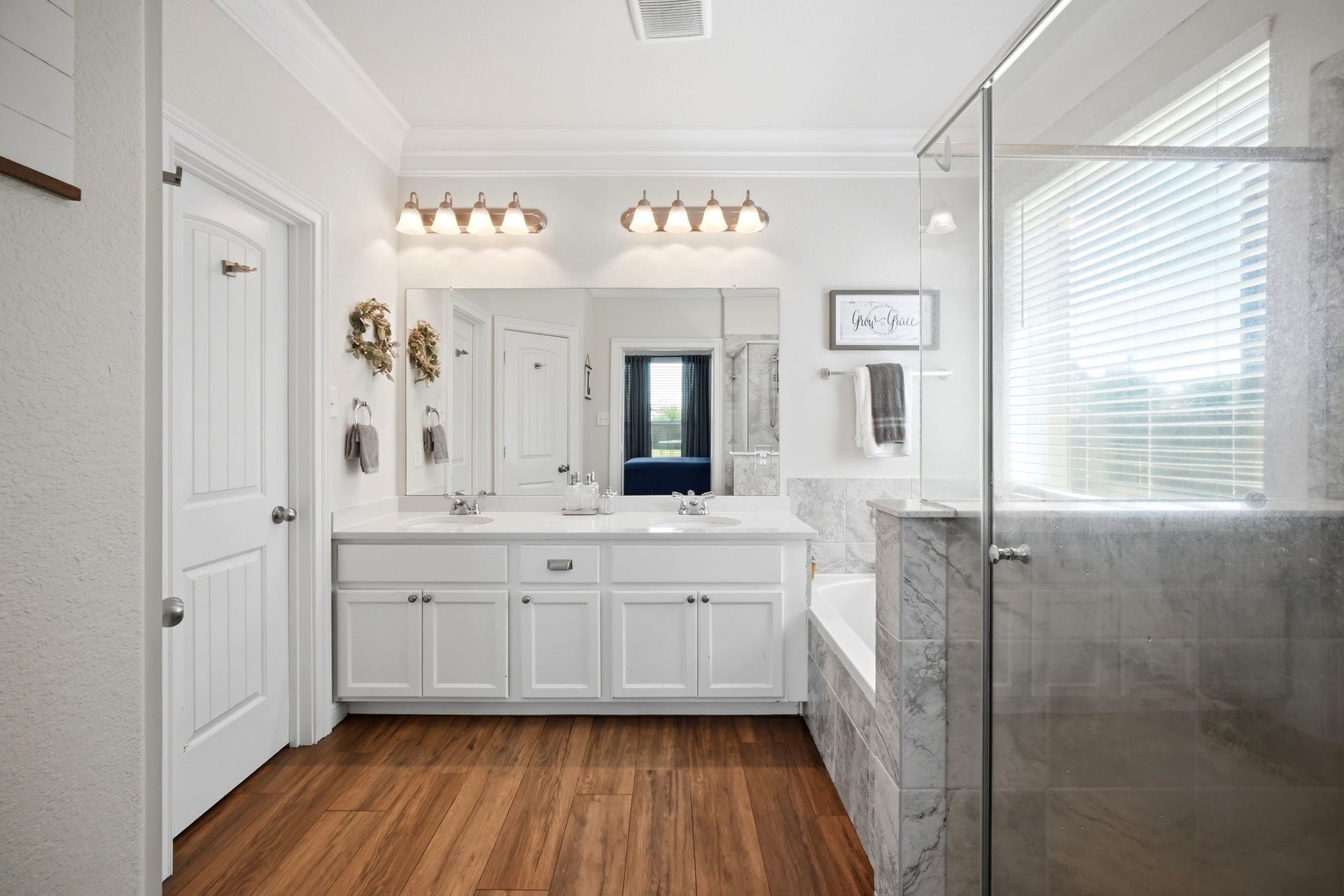 21639 Lexor Drive, Porter, TX 77365 Spacious bathroom featuring dual sinks, elegant lighting, and a luxurious glass-enclosed shower alongside a soaking tub, all highlighted by sleek accents and warm flooring.