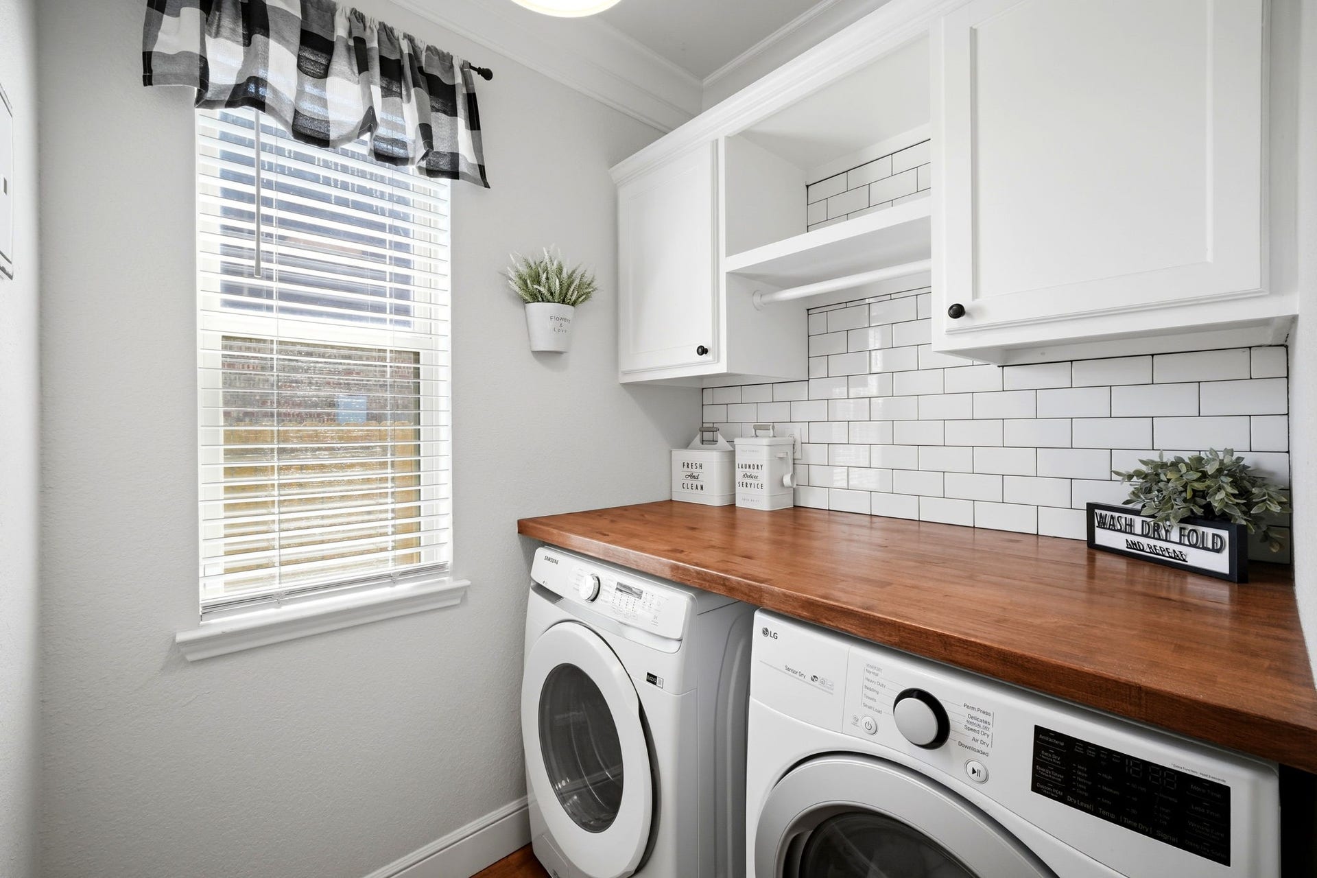 21639 Lexor Drive, Porter, TX 77365 Charming laundry room featuring modern appliances, subway tile backsplash, and ample storage with a wooden countertop, all illuminated by natural light from a large window.