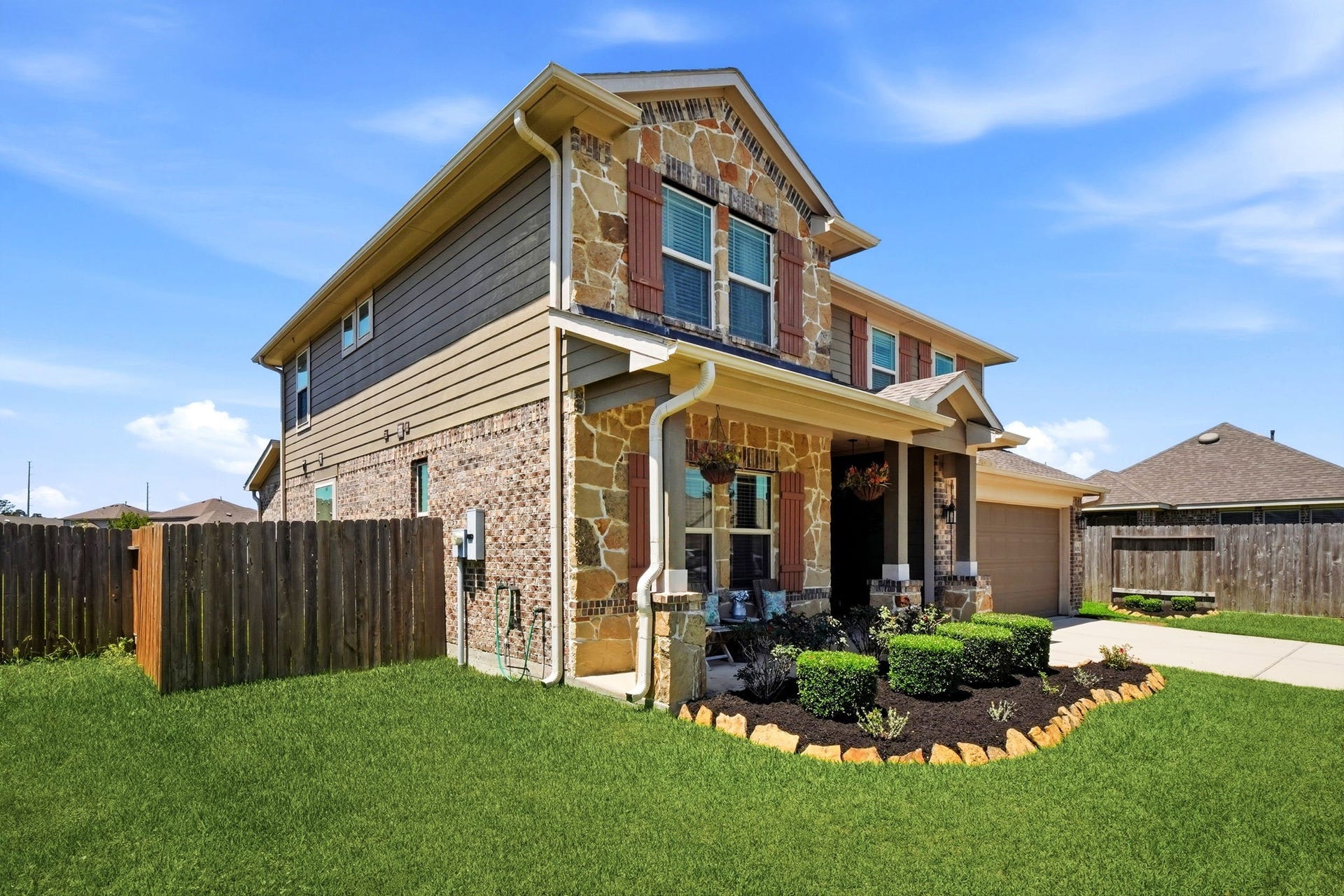 21639 Lexor Drive, Porter, TX 77365 Stunning two-story home with charming stone and brick exterior, featuring a welcoming covered porch and beautifully landscaped front yard.