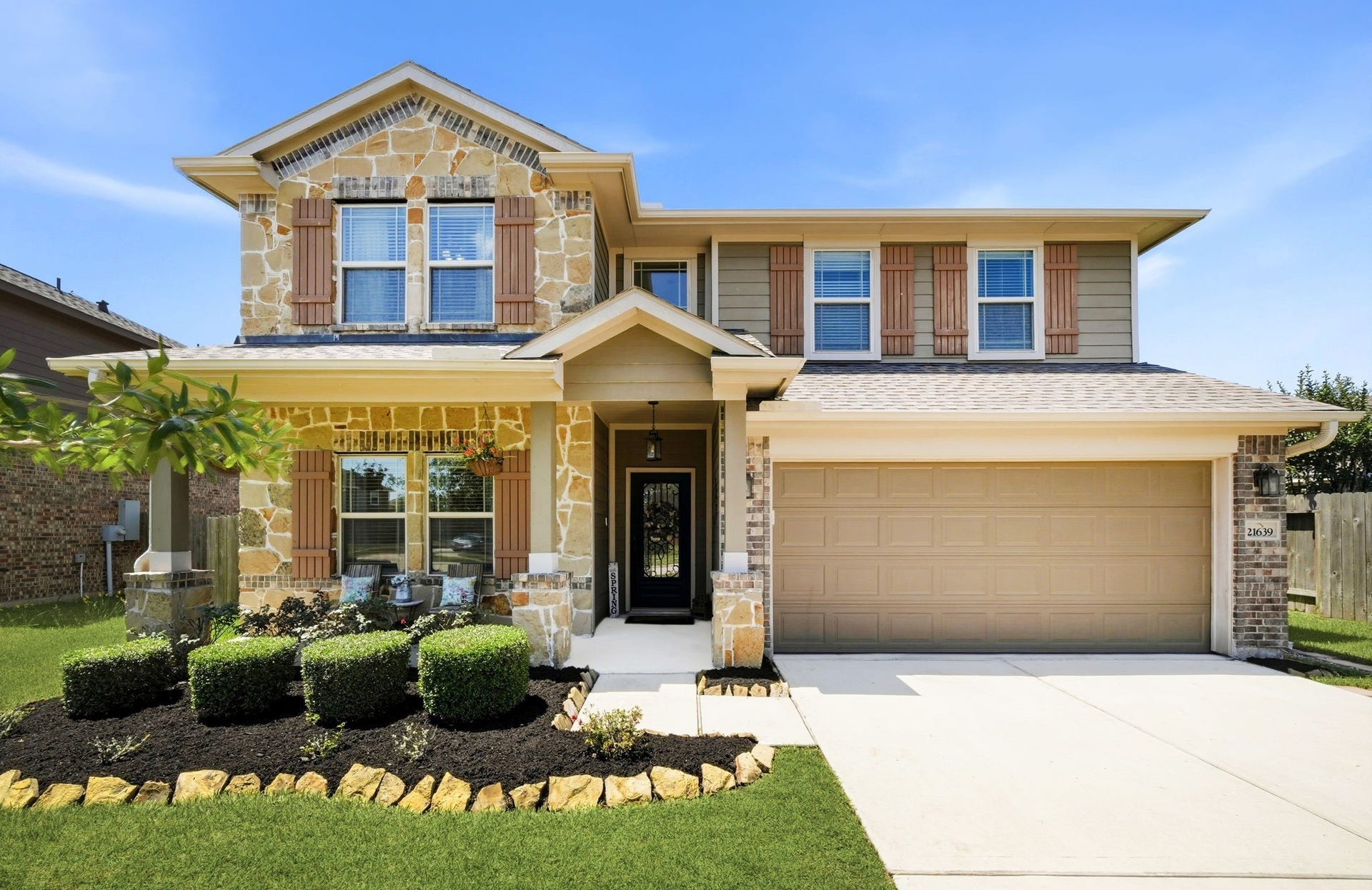 21639 Lexor Drive, Porter, TX 77365 Charming two-story home with a beautiful stone and brick exterior, featuring a welcoming front porch, manicured landscaping, and a spacious two-car garage.