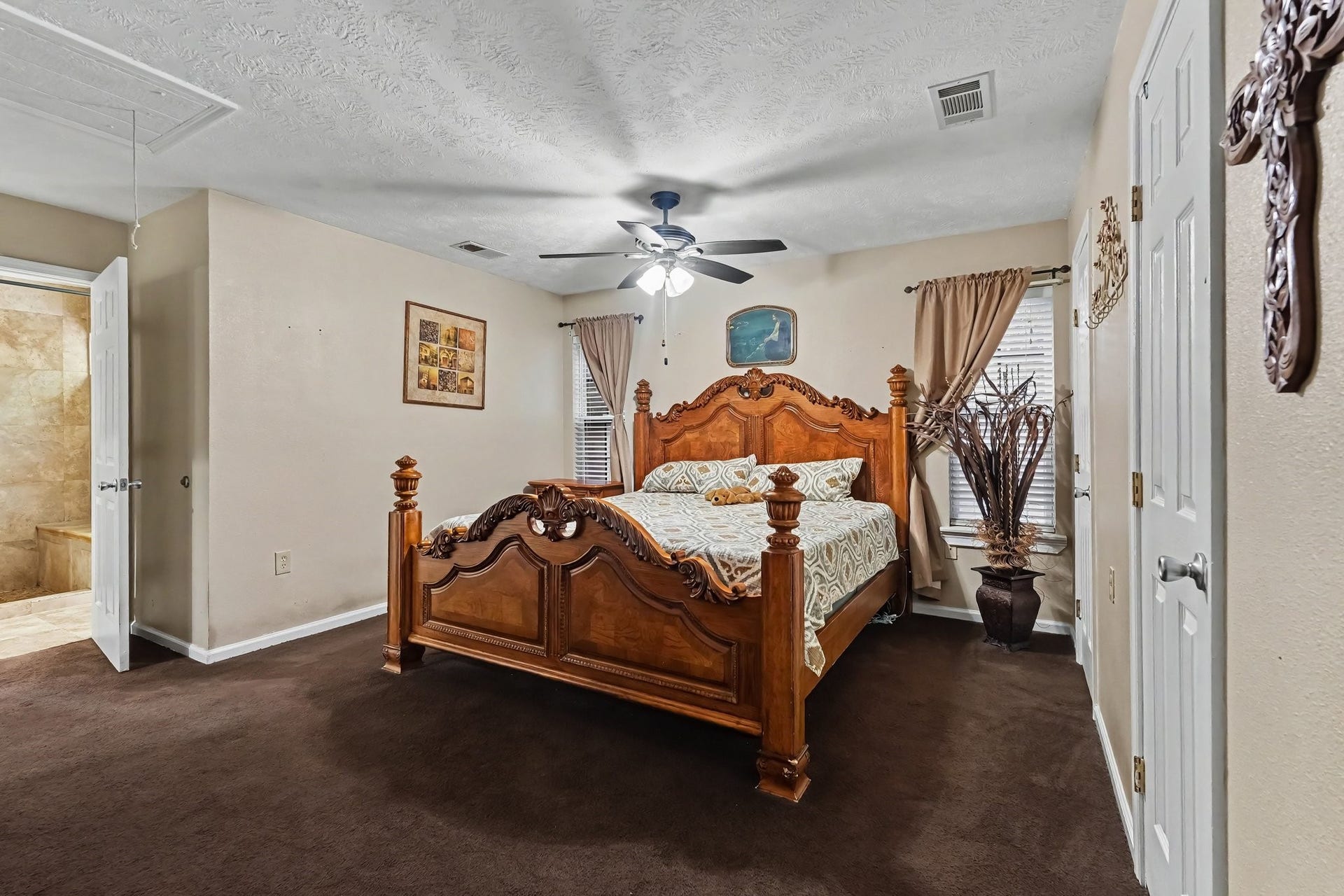 24609 Willow Lane, Hockley, TX 77447 Generously sized primary bedroom with multiple windows, ceiling fan, and convenient access to the en-suite bathroom.