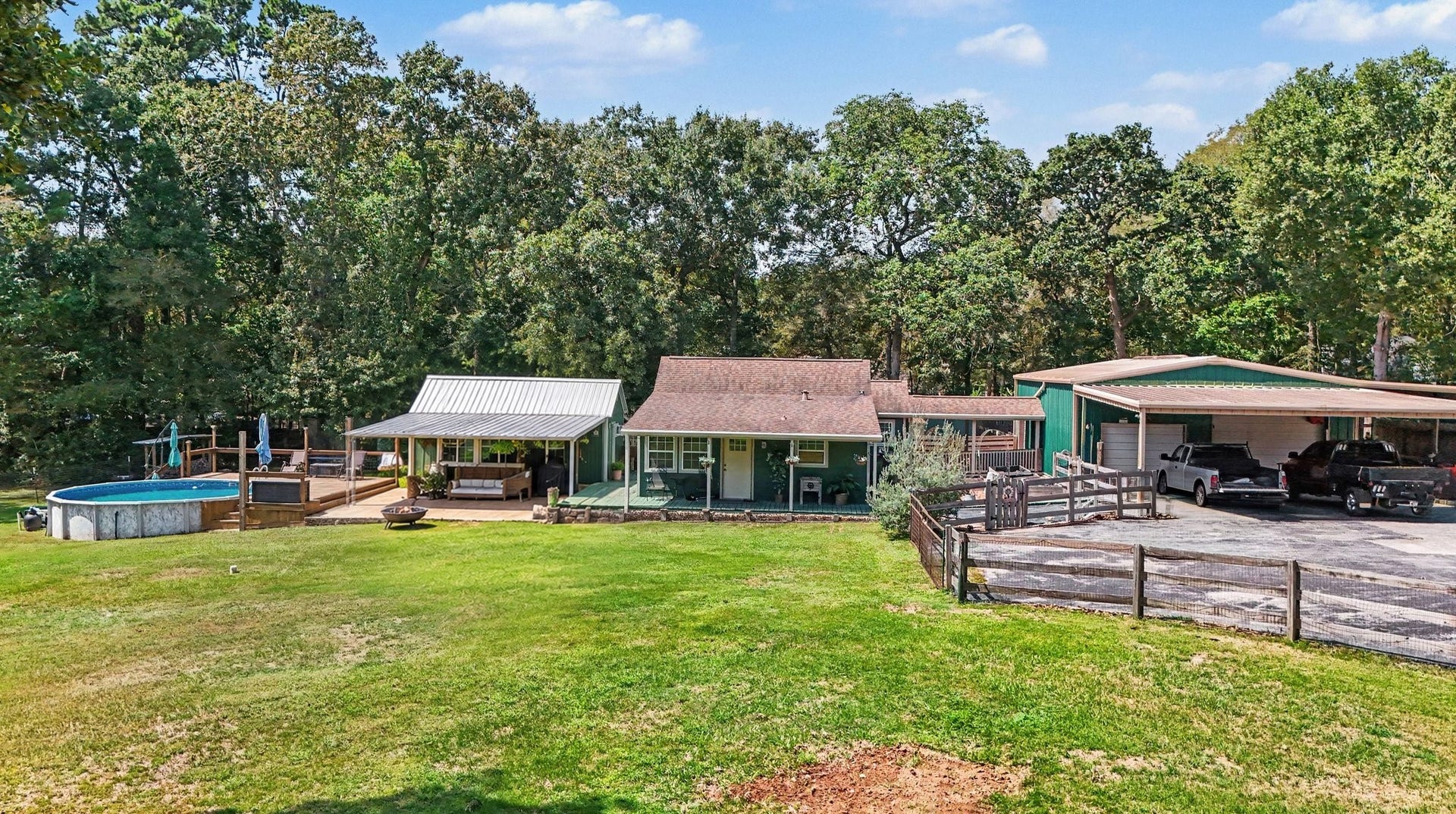 24609 Willow Lane, Hockley, TX 77447 Elevated view showcasing the home, pool, outdoor living areas, workshop, covered parking, and expansive yard surrounded by mature trees. Virtually staged patio furniture.