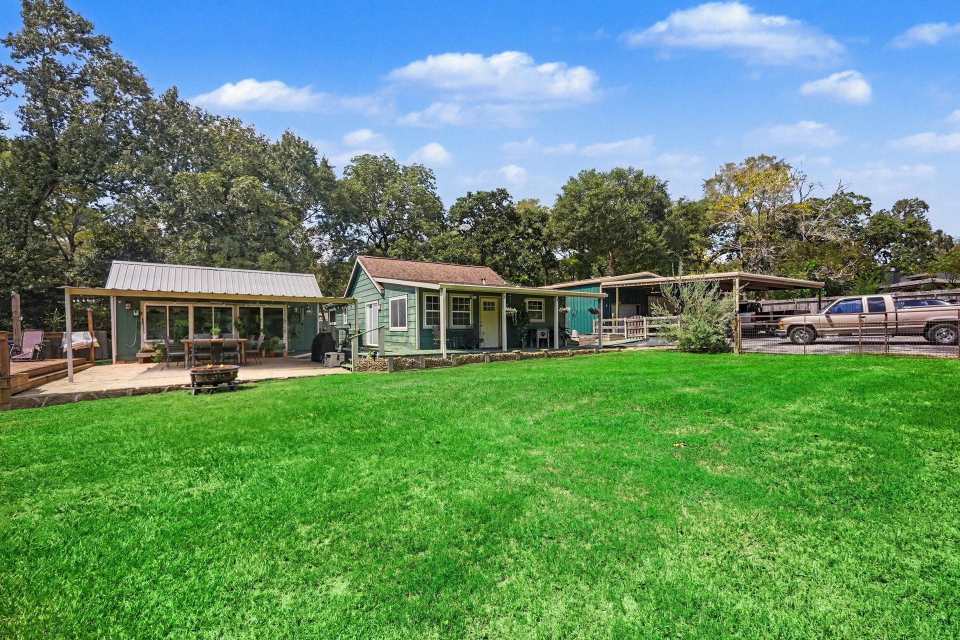 24609 Willow Lane, Hockley, TX 77447 Wide front view showcasing the home, covered patio, outdoor living areas, workshop/covered parking, and expansive lawn