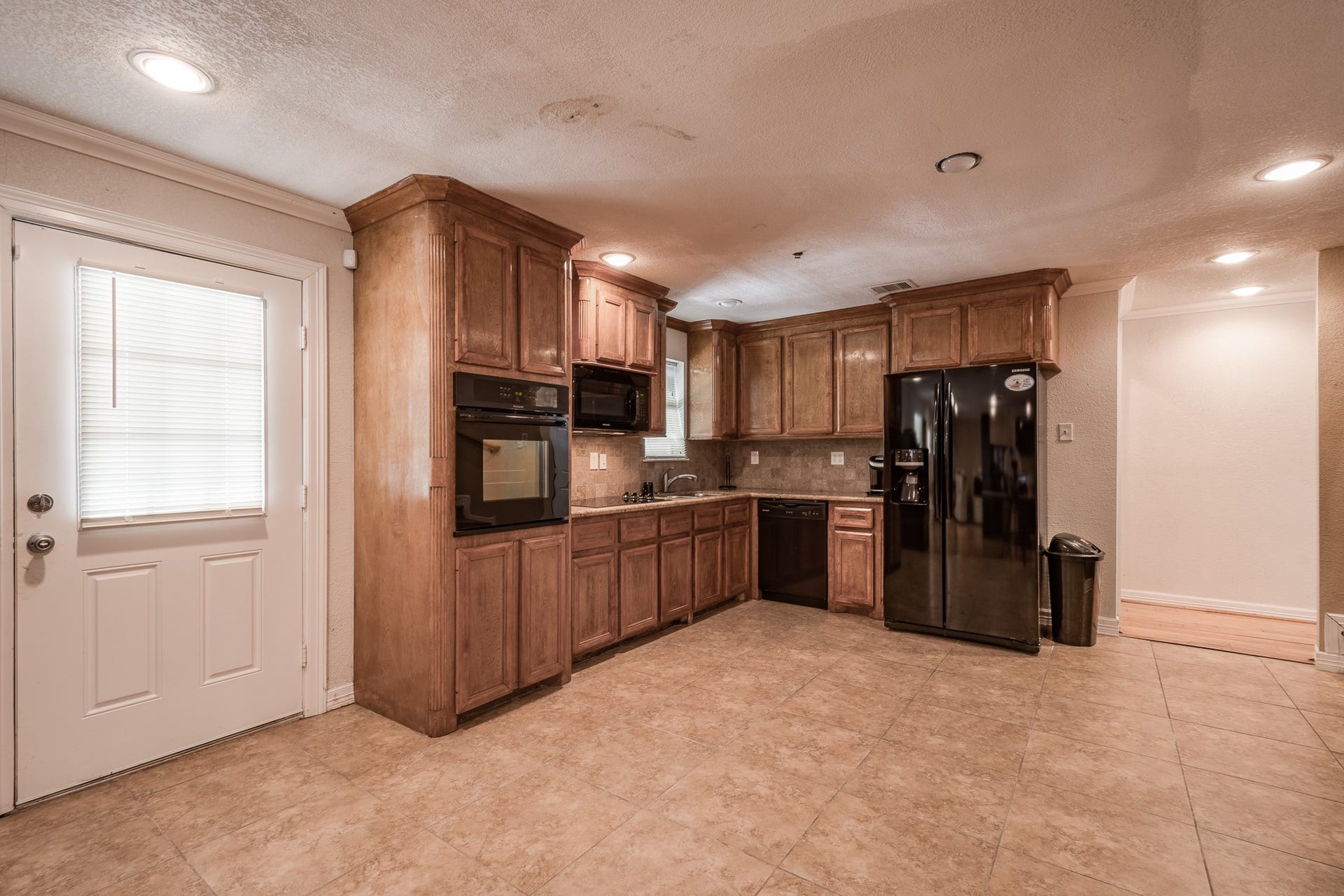 16111 Porter Lane, Porter, TX 77365 Spacious kitchen featuring rich wooden cabinetry, modern appliances, and ample natural light from the adjacent door, creating a warm and inviting atmosphere.