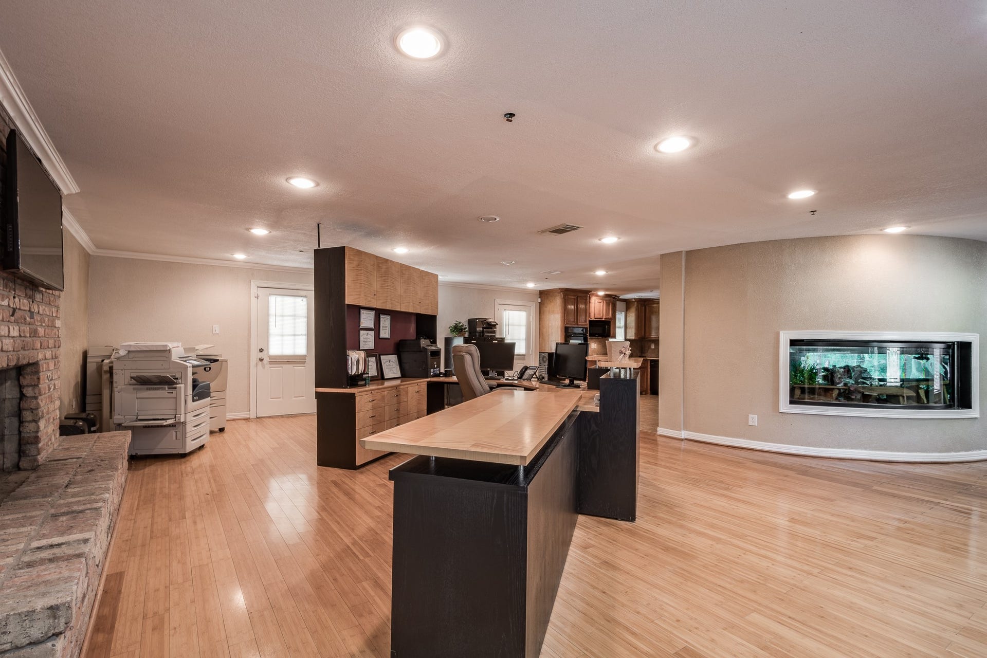 16111 Porter Lane, Porter, TX 77365 Spacious home office with sleek wood flooring, built-in desk, and a cozy brick fireplace, perfect for work and relaxation.