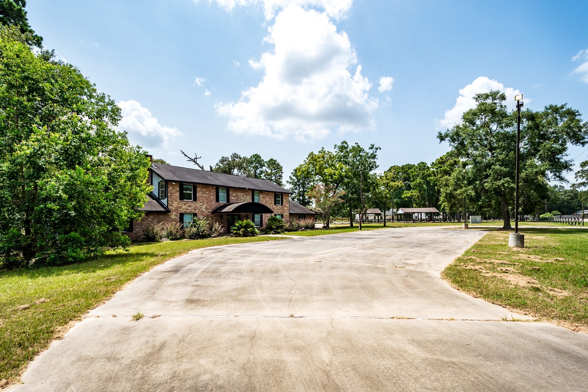 16111 Porter Lane, Porter, TX 77365 Spacious brick home with a long driveway, surrounded by lush greenery and mature trees, offering a serene and inviting atmosphere.