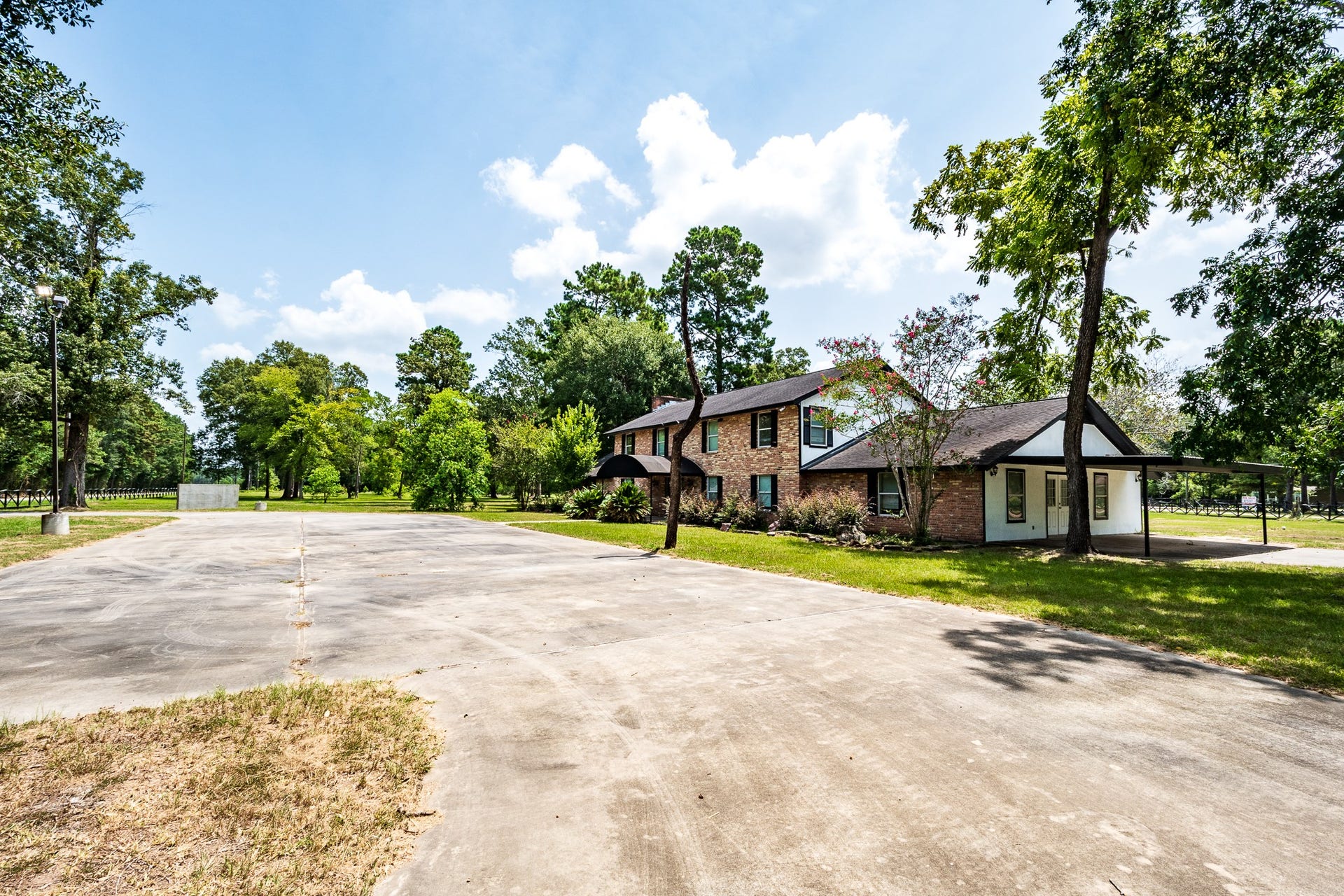 16111 Porter Lane, Porter, TX 77365 Two-story brick home set amidst lush greenery, featuring a wide driveway and ample outdoor space for recreation and relaxation.