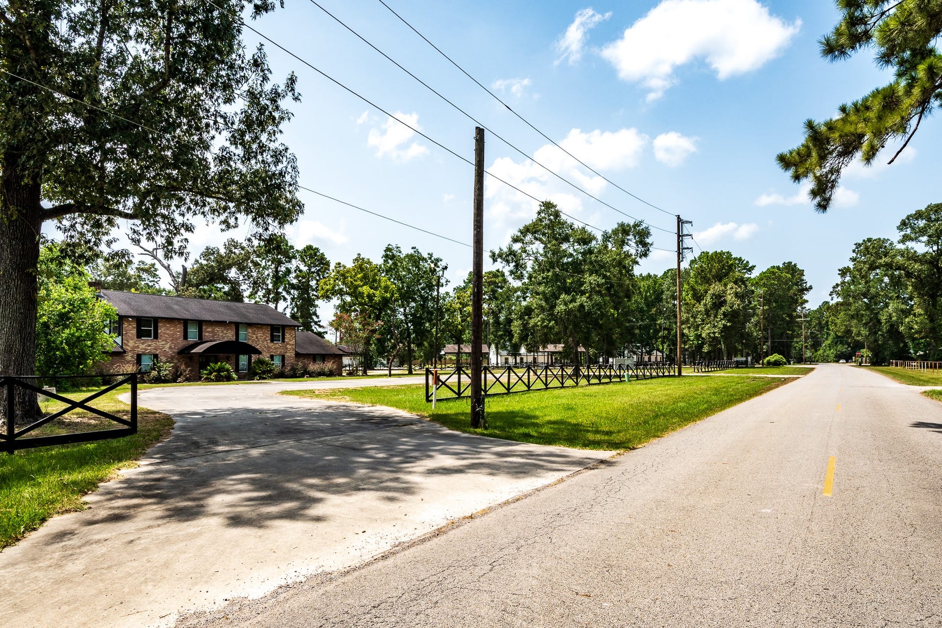 16111 Porter Lane, Porter, TX 77365 Charming brick home with a welcoming driveway, nestled among mature trees and expansive greenery, offering a serene, country-style setting.