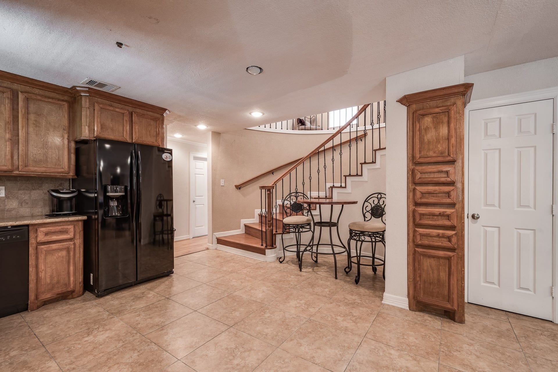 16111 Porter Lane, Porter, TX 77365 Charming kitchen area with elegant wood cabinetry, sleek black appliances, and a cozy dining nook next to a graceful staircase.