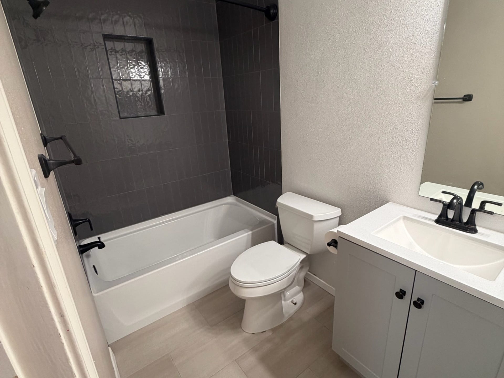 3500 Tangle Brush Drive, #65, The Woodlands, TX 77381 Primary bath redone with a new tub, dark tile surround, shaker vanity, black fixtures, and new lighting.