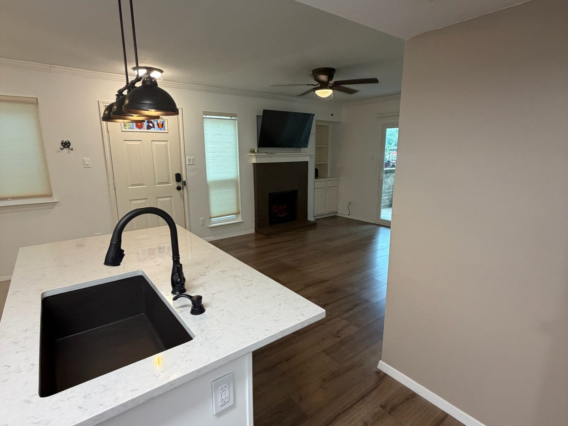 3500 Tangle Brush Drive, #65, The Woodlands, TX 77381 Inviting living area features warm wood-look flooring, a cozy fireplace with built-in storage, crown molding, and natural light, all within an open layout that keeps the kitchen and living spaces connected.