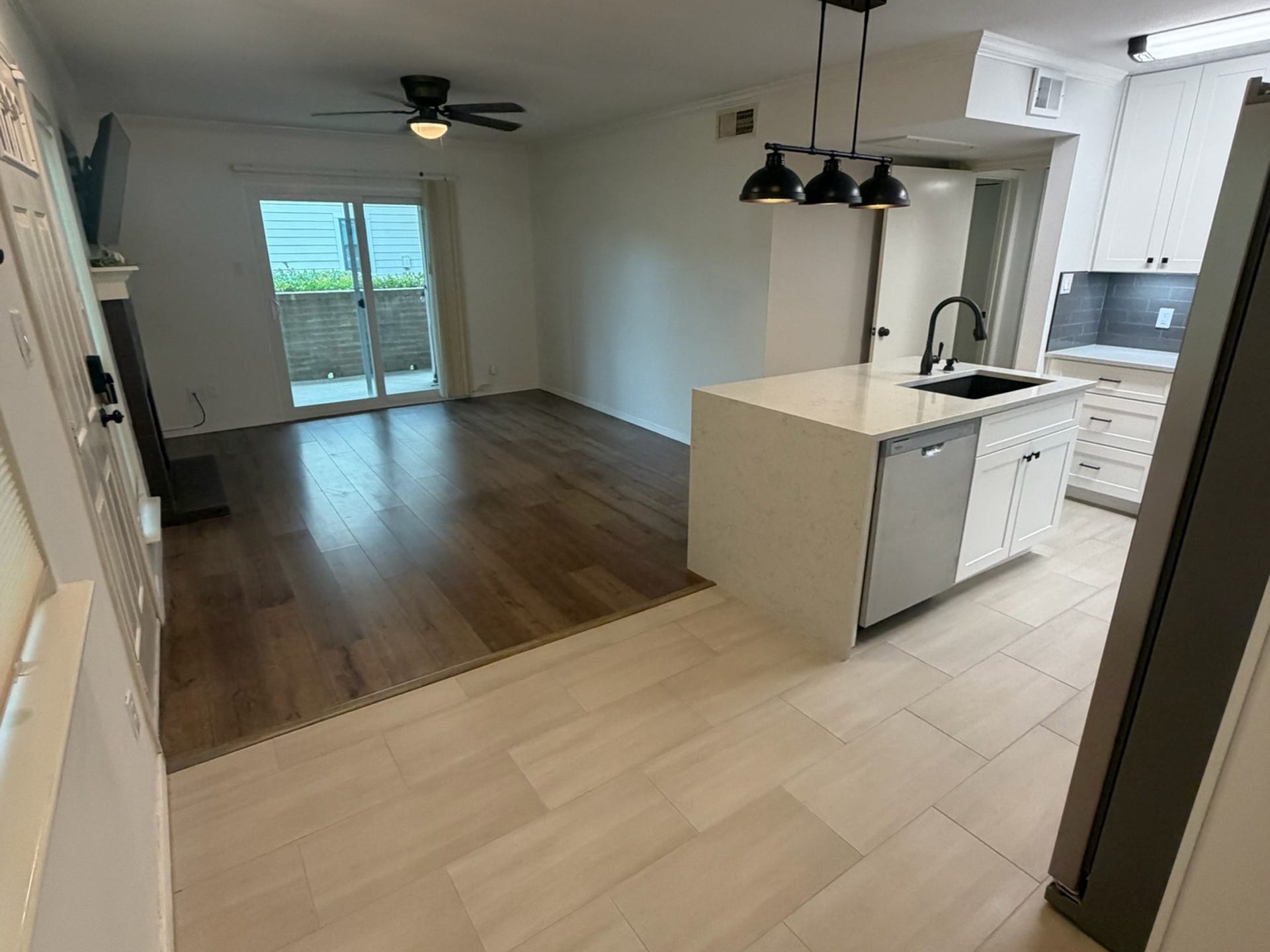 3500 Tangle Brush Drive, #65, The Woodlands, TX 77381 Open living area flows seamlessly from the kitchen, with warm wood-look flooring, a ceiling fan, and sliding glass doors bringing in natural light and providing direct access to the private patio.