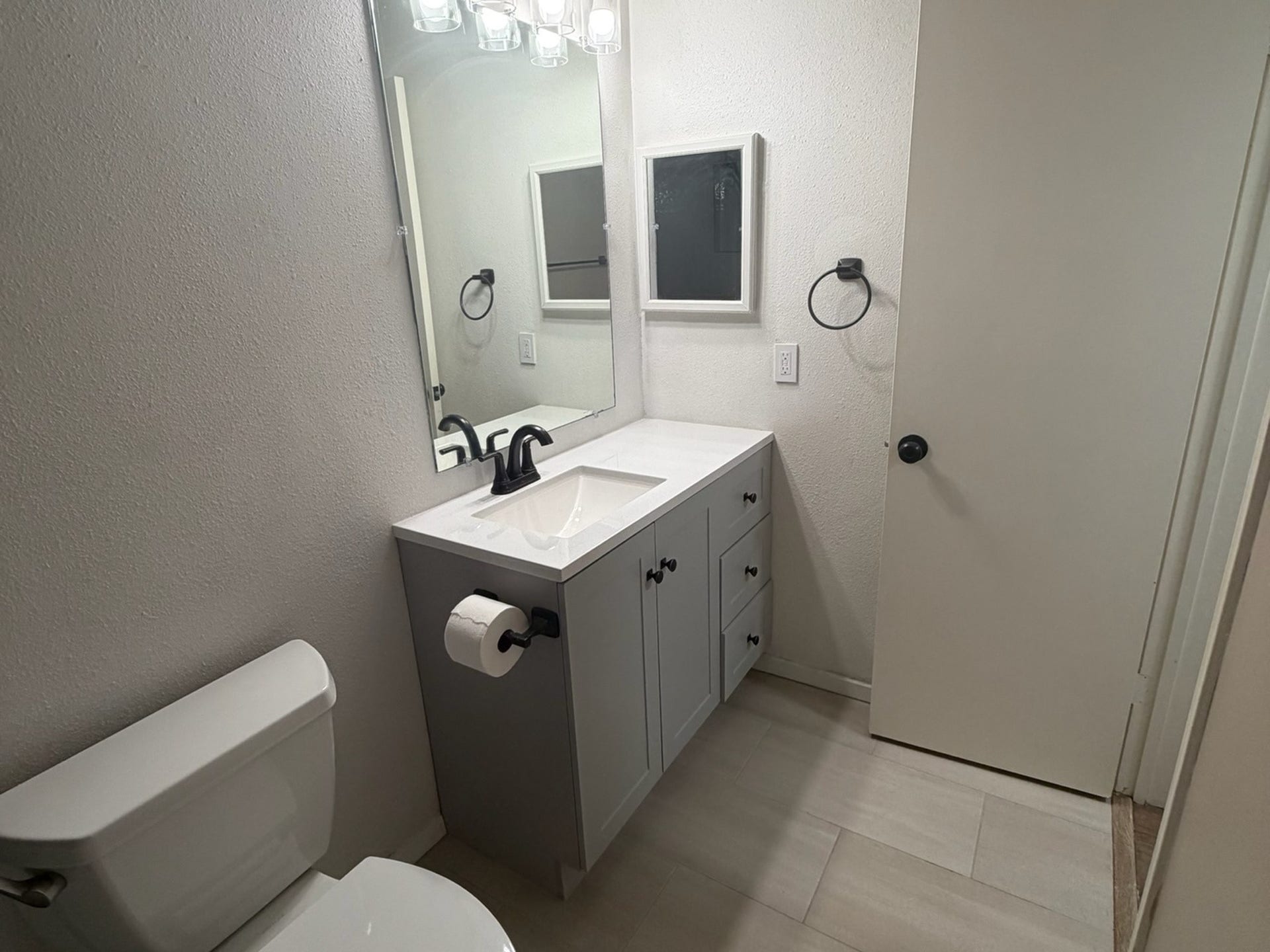 3500 Tangle Brush Drive, #65, The Woodlands, TX 77381 Updated bathroom vanity features shaker-style cabinetry, a bright countertop with integrated sink, modern black fixtures and hardware, a large mirror, and light tile flooring for a clean, cohesive look.