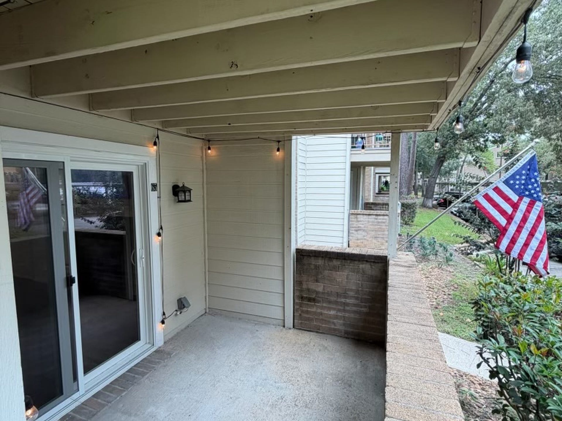 3500 Tangle Brush Drive, #65, The Woodlands, TX 77381 Private covered patio extends the living space outdoors, with direct access from the living room and a brick half-wall that adds separation while maintaining an open feel.