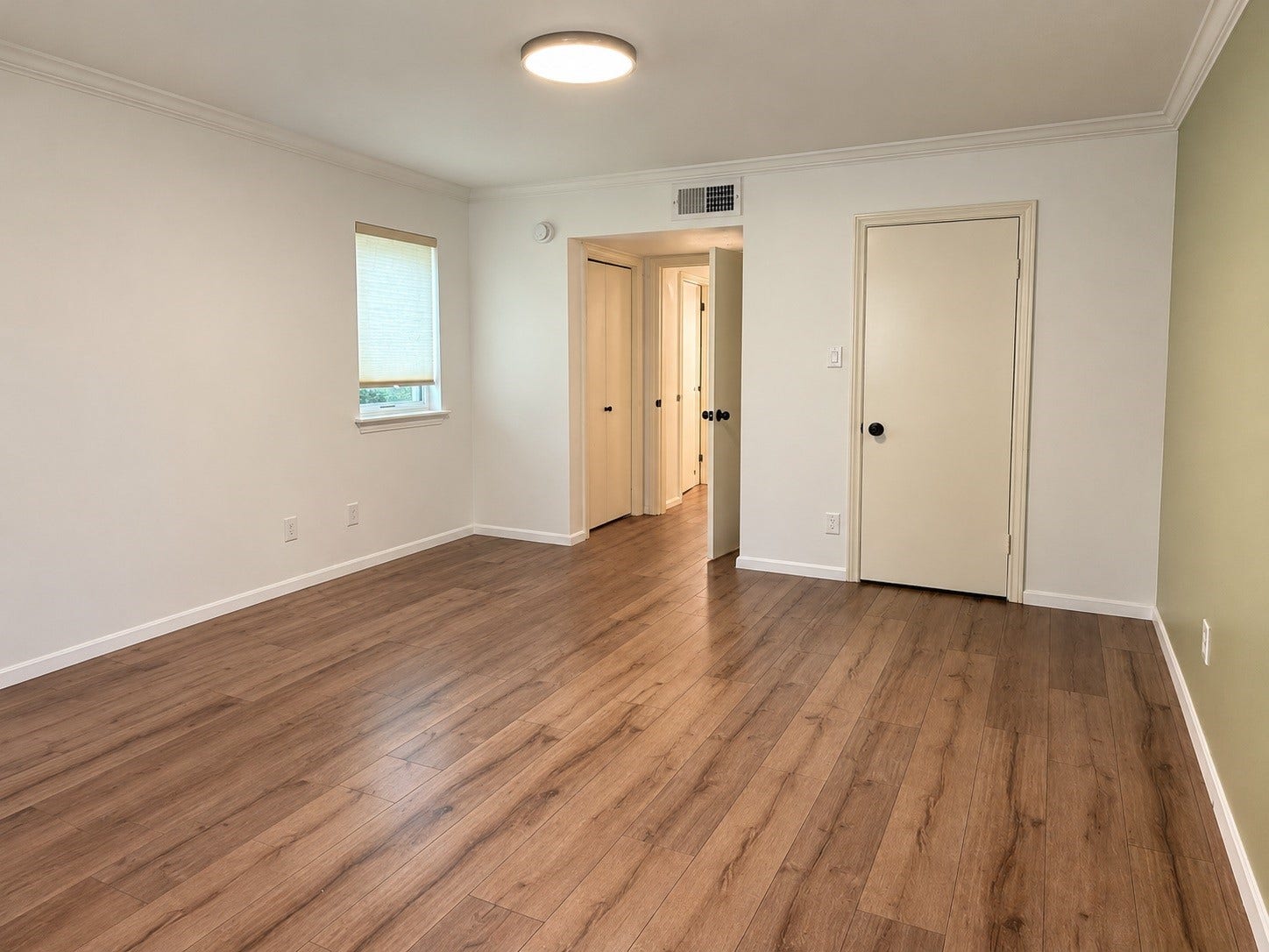 3500 Tangle Brush Drive, #65, The Woodlands, TX 77381 Generously sized primary bedroom features warm wood-look flooring, crown molding, a neutral color palette, and natural light, with plenty of flexibility for a full bedroom suite and additional furnishings.
