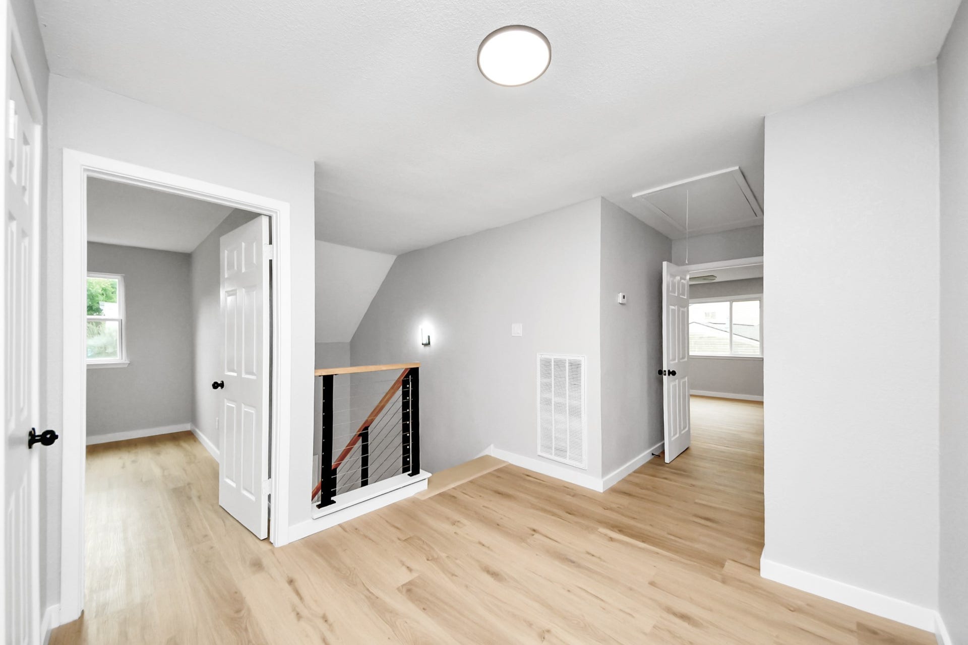 3234 Pebble Lake Drive, Sugar Land, TX 77479 Bright, open hallway with light wood flooring and modern gray walls. It features two doors leading to rooms, a staircase with sleek railing, and ample natural light. Perfect for a contemporary home.