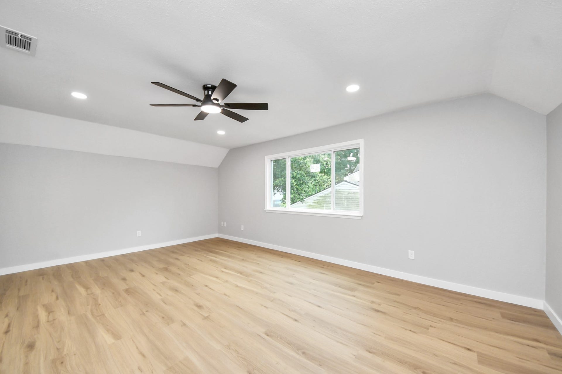 3234 Pebble Lake Drive, Sugar Land, TX 77479 Spacious 5th bedroom features elegant light wood flooring, neutral gray walls, and a modern ceiling fan. It has recessed lighting and a large window with a view of greenery, offering plenty of natural light.