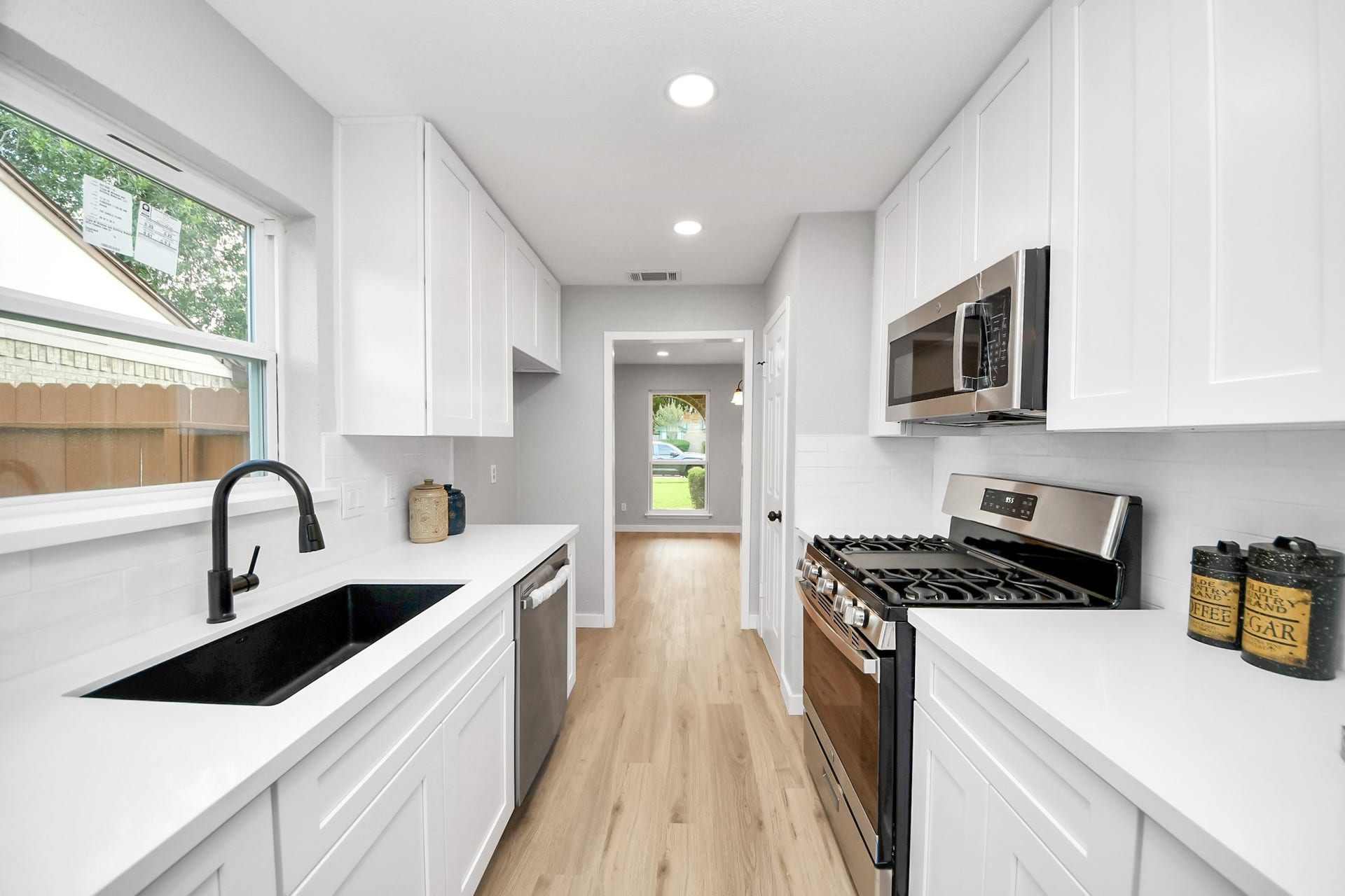3234 Pebble Lake Drive, Sugar Land, TX 77479 This bright, modern kitchen features sleek white cabinetry, stainless steel appliances, and a black sink. The light wood flooring and ample natural light create an inviting atmosphere.