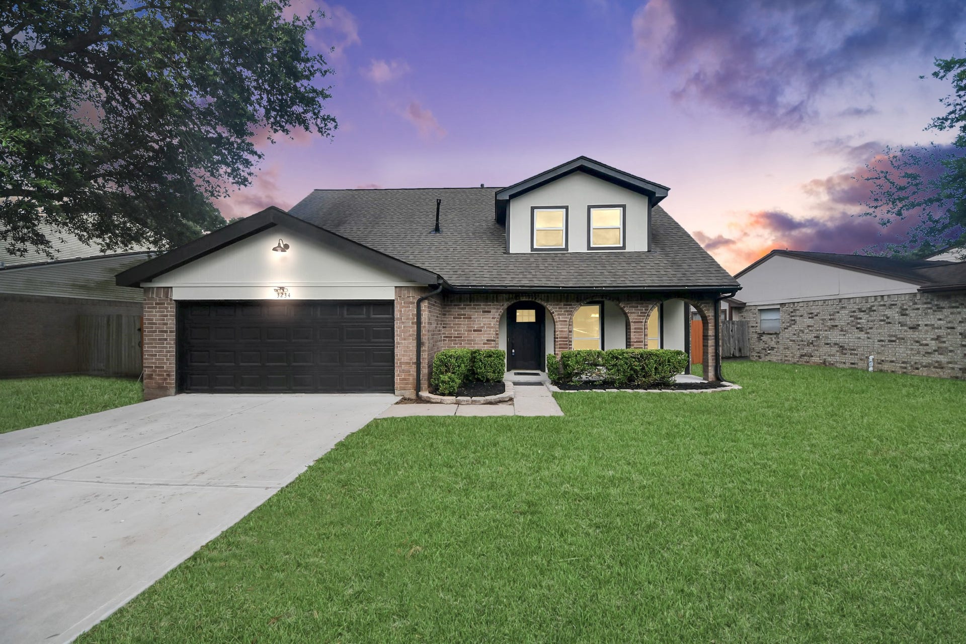 3234 Pebble Lake Drive, Sugar Land, TX 77479 This two-story brick home features a contemporary design with a spacious front lawn, a two-car garage, and a charming covered entryway. The sunset backdrop adds a warm, inviting atmosphere.
