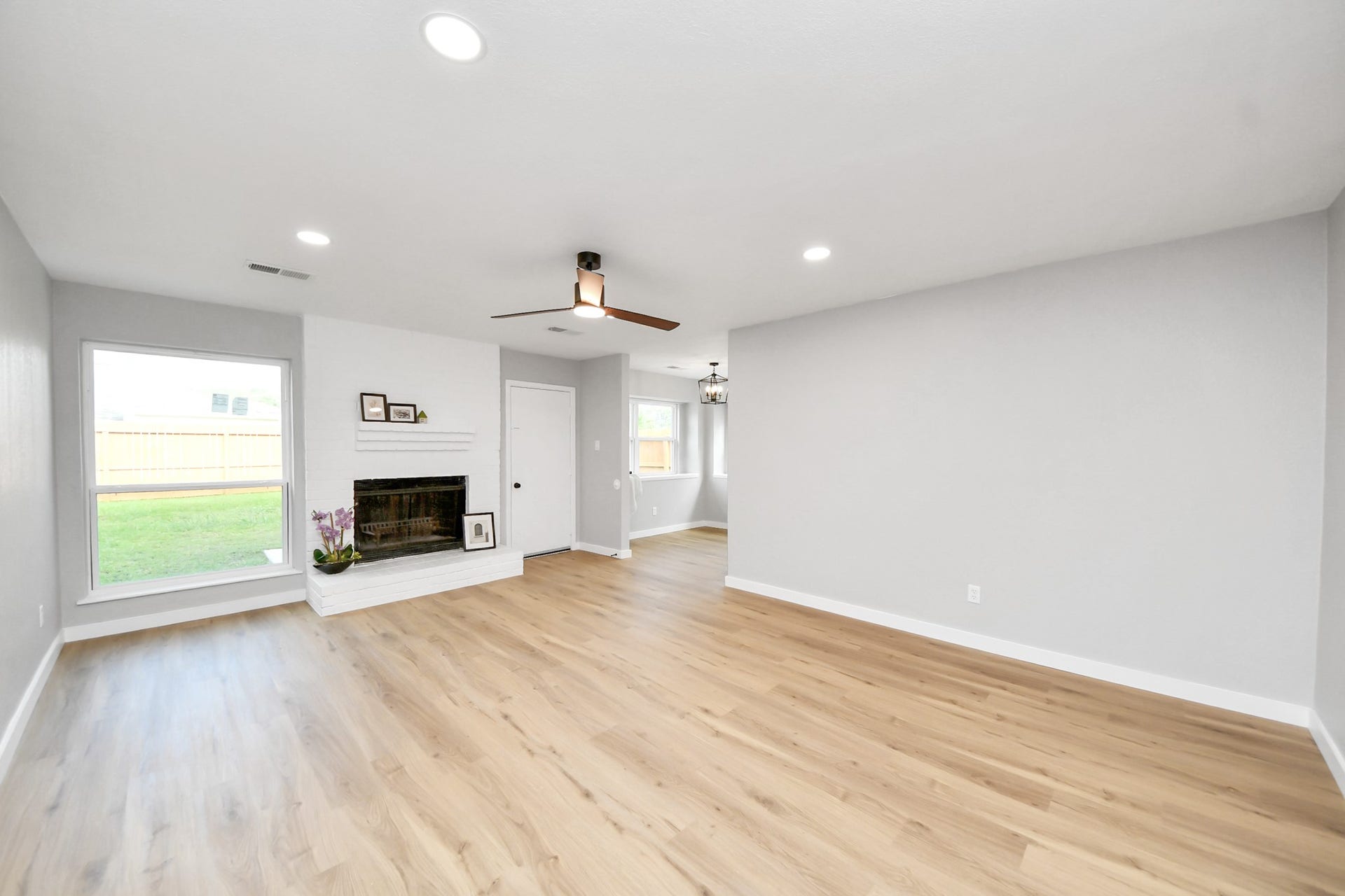 3234 Pebble Lake Drive, Sugar Land, TX 77479 This spacious living area features light wood flooring, a modern ceiling fan, and ample natural light from large windows. A cozy fireplace adds charm, and the neutral walls create a versatile backdrop for any decor style.