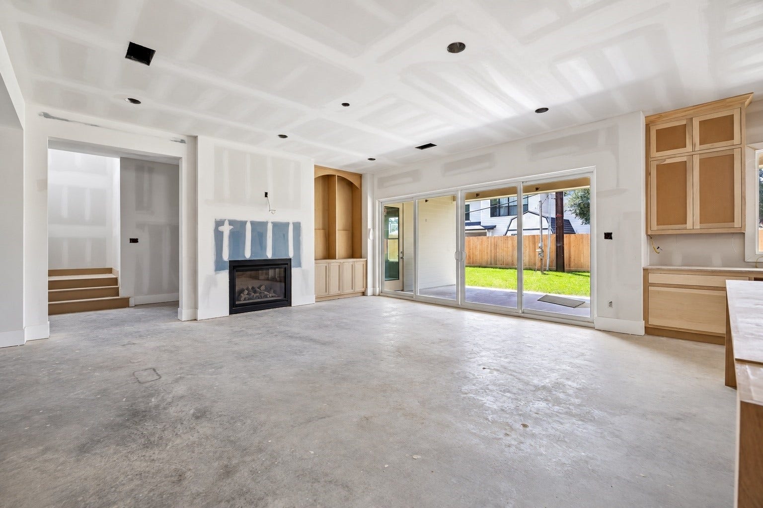 Anchored by a fireplace and custom built ins, the spacious living room opens directly to the covered veranda and backyard through a wide wall of glass doors. Natural light and seamless indoor outdoor flow make this space equally suited for everyday living and entertaining. **Current Construction as of 9/11/26
