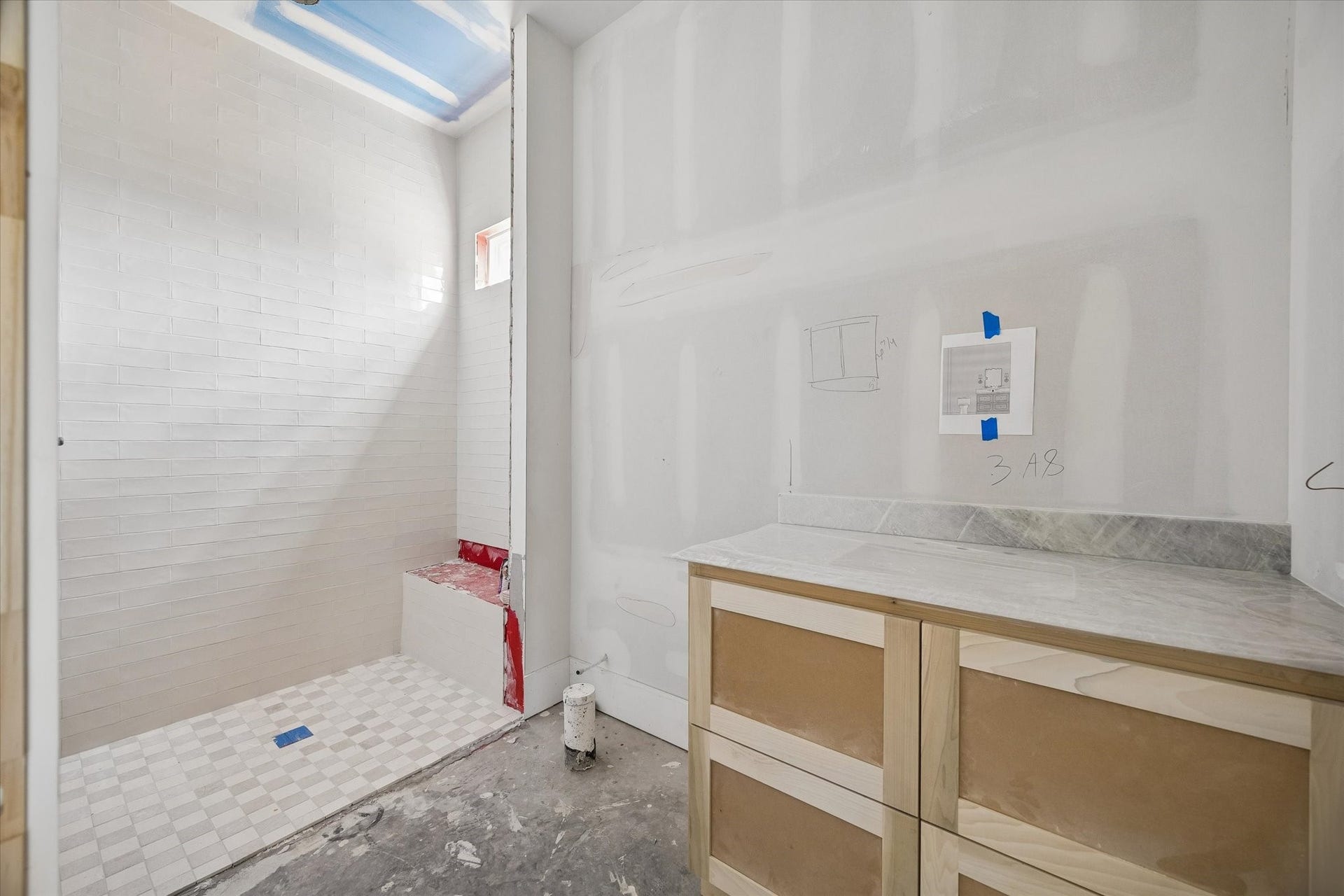 Soft neutral tile brings a clean, timeless finish to this guest bathroom, while the walk in shower features floor to ceiling tile and a built in bench. Natural light from the shower window keeps the space bright and airy. **Current Construction as of 9/11/26