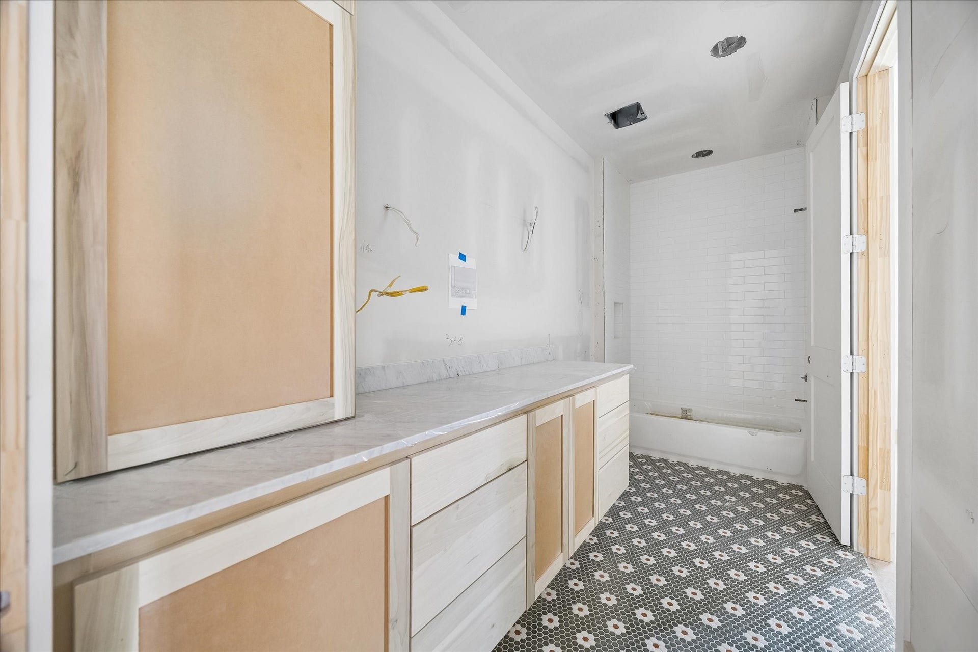 Patterned mosaic tile brings personality to this ensuite bath, balanced by warm custom cabinetry and a long stone topped vanity. Full height shower tile and a built in niche continue the thoughtful finish selections. **Current Construction as of 9/11/26