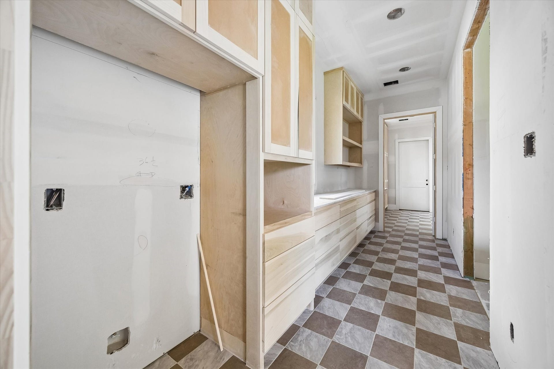 Designed to keep prep and cleanup tucked away from the main kitchen, the spacious scullery offers extensive custom cabinetry, long stretches of counter space, and dedicated appliance zones. Checkerboard flooring brings a distinctive design moment to this hardworking secondary kitchen space. **Current Construction as of 9/11/26