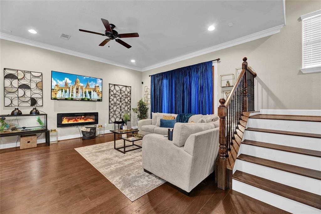 14502 San Pietro Drive, Houston, TX 77070 Spacious living room featuring elegant hardwood floors, a cozy fireplace, and a modern entertainment setup!