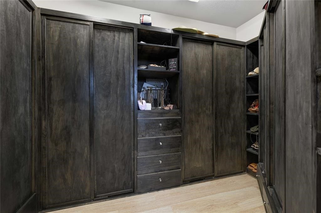 14502 San Pietro Drive, Houston, TX 77070 Expansive walk-in closet featuring rich, dark wood cabinetry with ample shelving and drawers for organized storage!