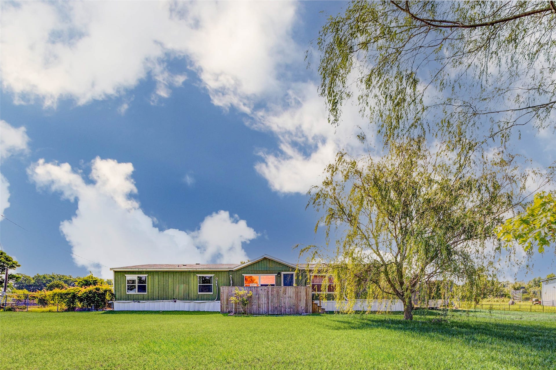 333 County Road 4923, Dayton, TX 77535 A private wooden deck wraps around the front entry of the home, which is framed by durable vertical siding and a neat white foundation trim.