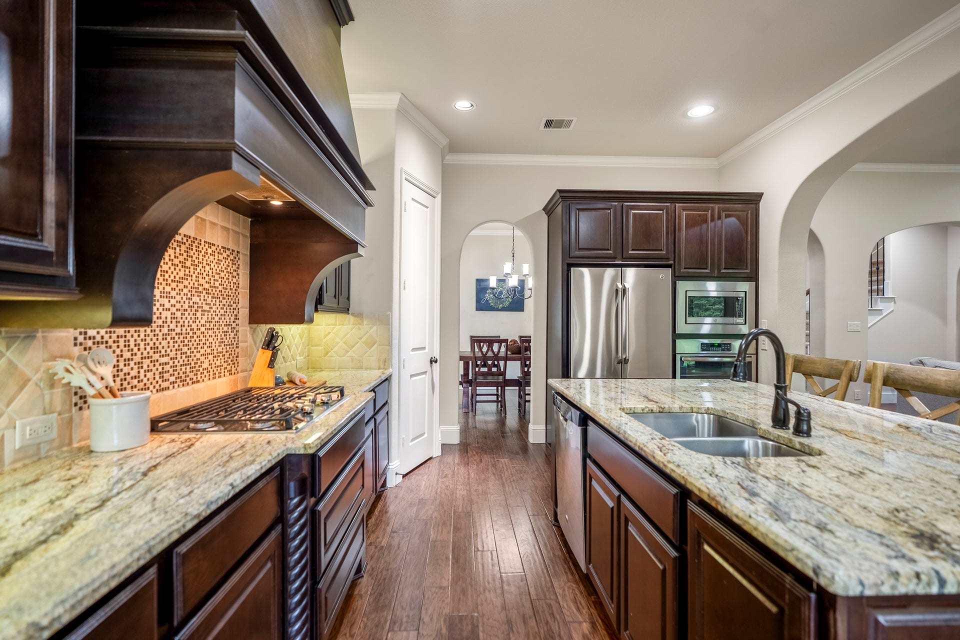 A gas range, double sink, ample cabinets and stainles steel appliances add the finishing touches to this designer kitchen.