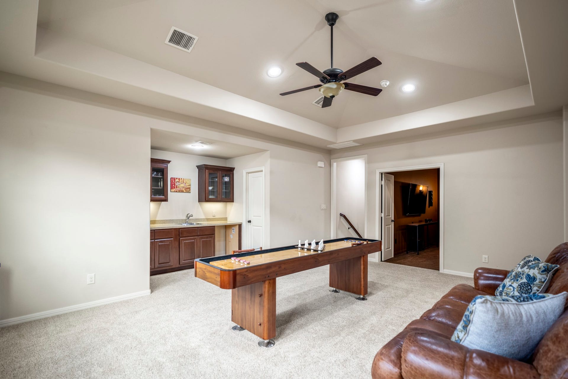 The large upstairs game room features a sink, cabinets, and countertop with room for a mini-fridge.