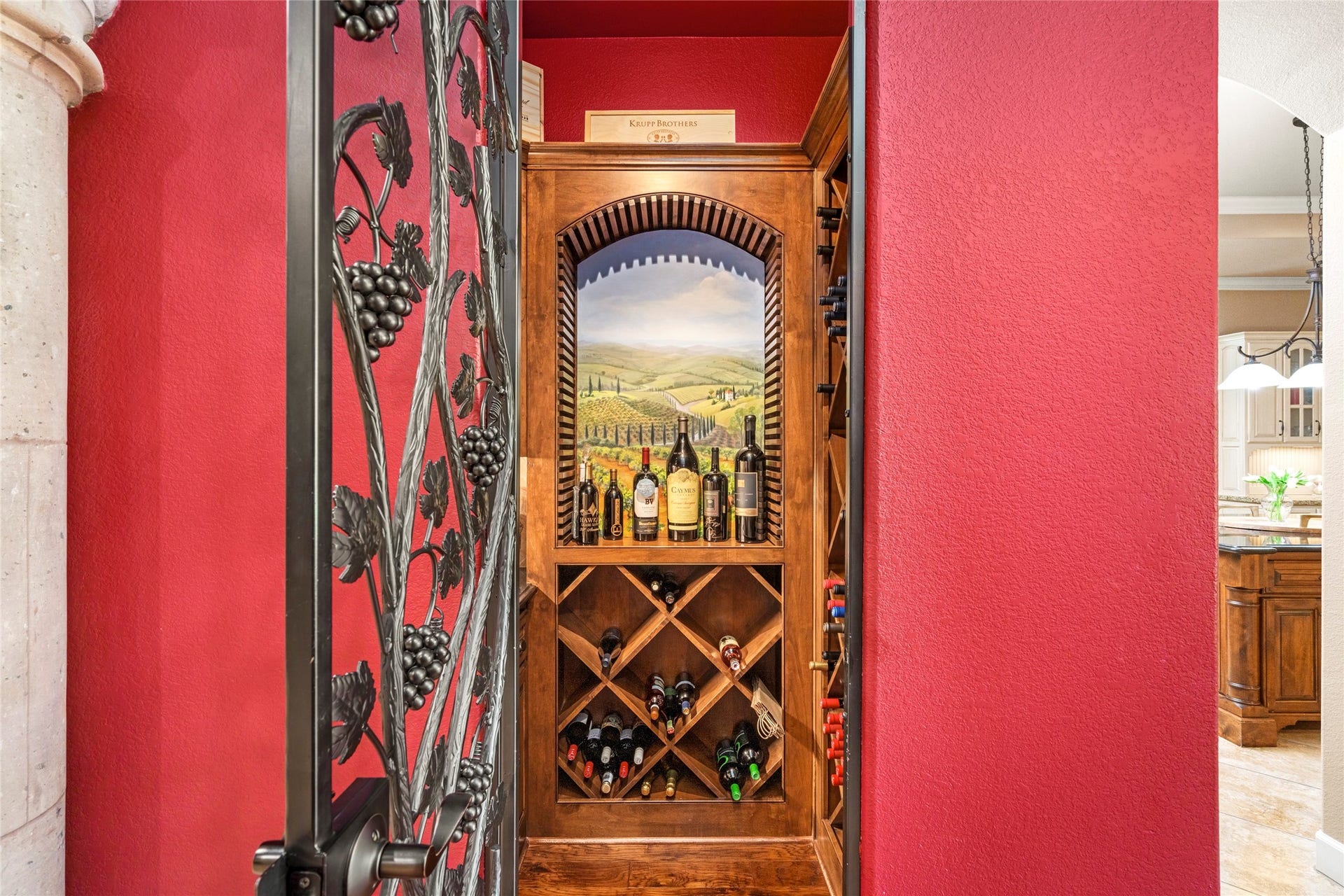 The wine room behind an iron door adorned with grape motifs, offers ample wine storage and evokes the charm of Italy's wine country.