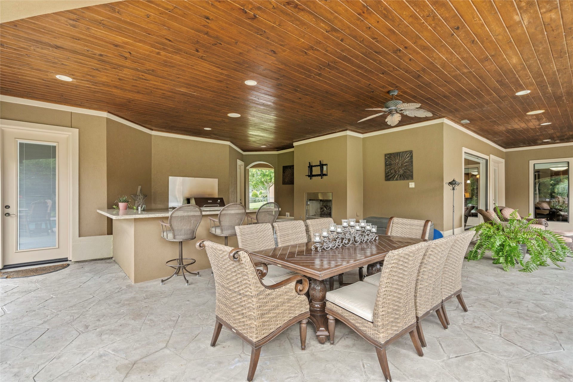 This covered area includes an outdoor kitchen & bar area, fireplace, and direct access to the private guest suite.