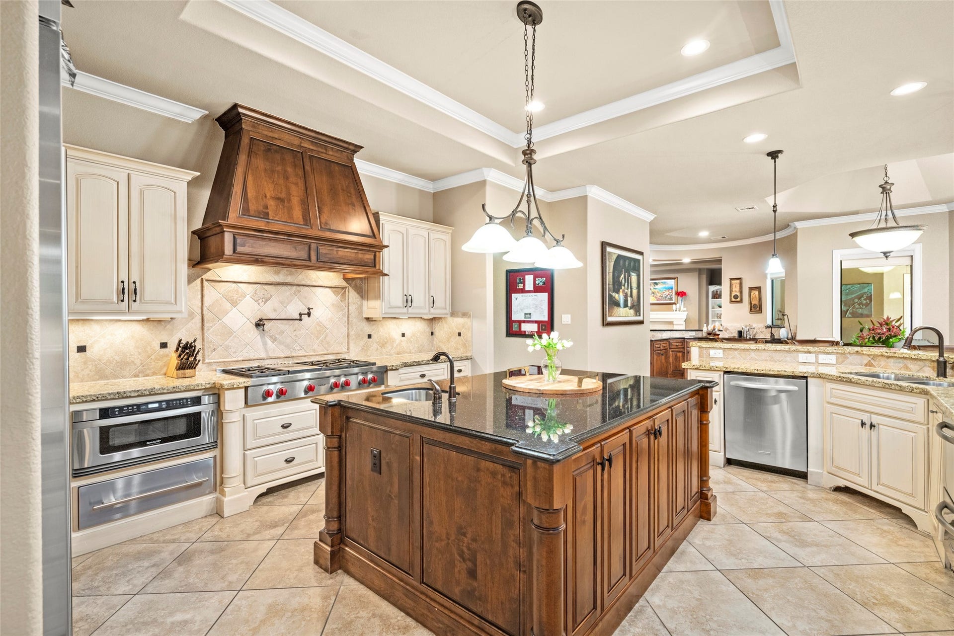 Gorgeous woodwork on the vent hood frames a 6-burner Wolf stove with a pot filler. Every chef-ready convenience you could want is in this kitchen. Dual dishwashers, microwave drawer, and a warming drawer.