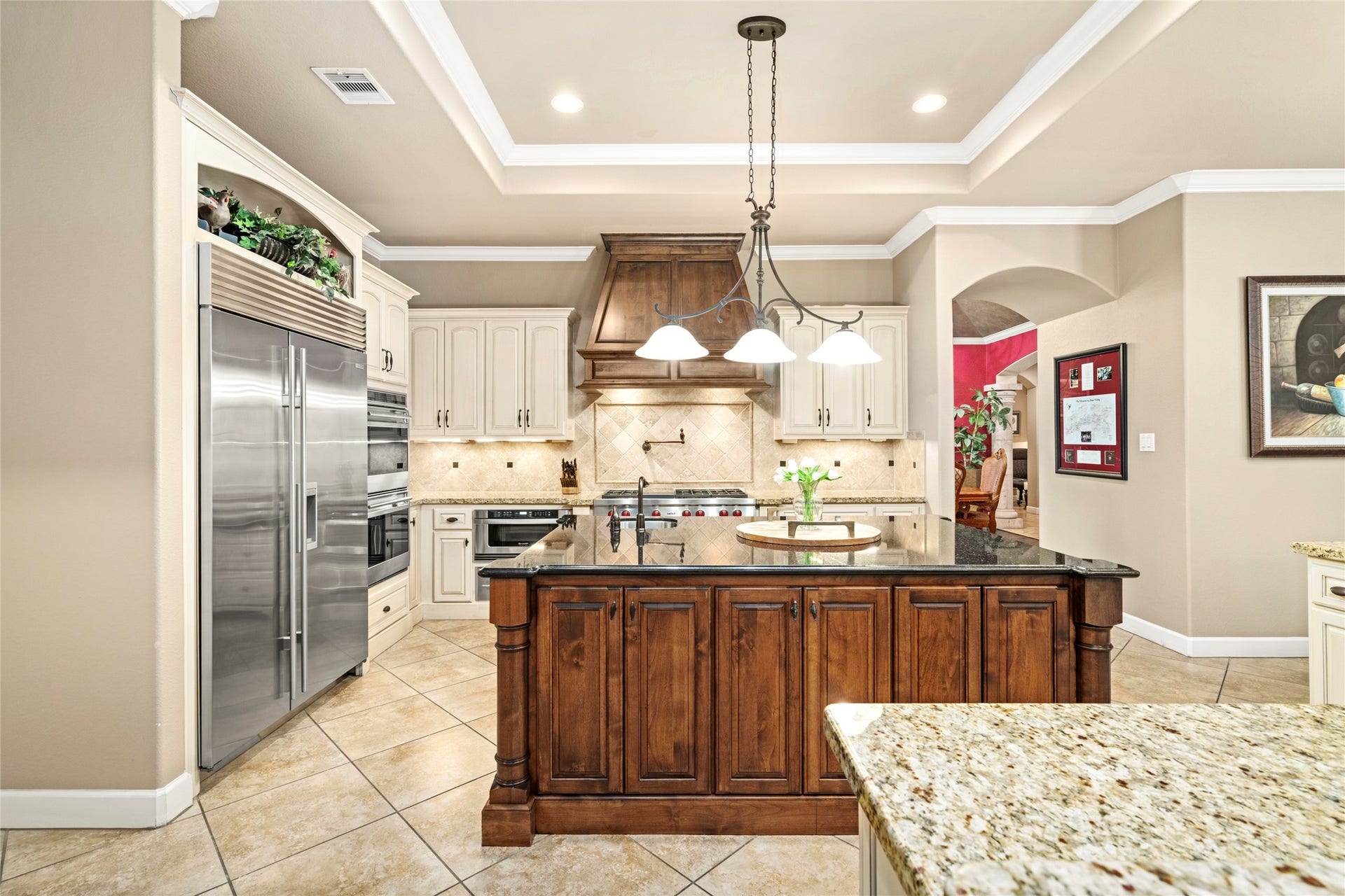 The island's exquisite woodwork and the striking hood vent elevate the kitchen's centerpiece, while the built in refrigerator completes a truly impressive culinary space.