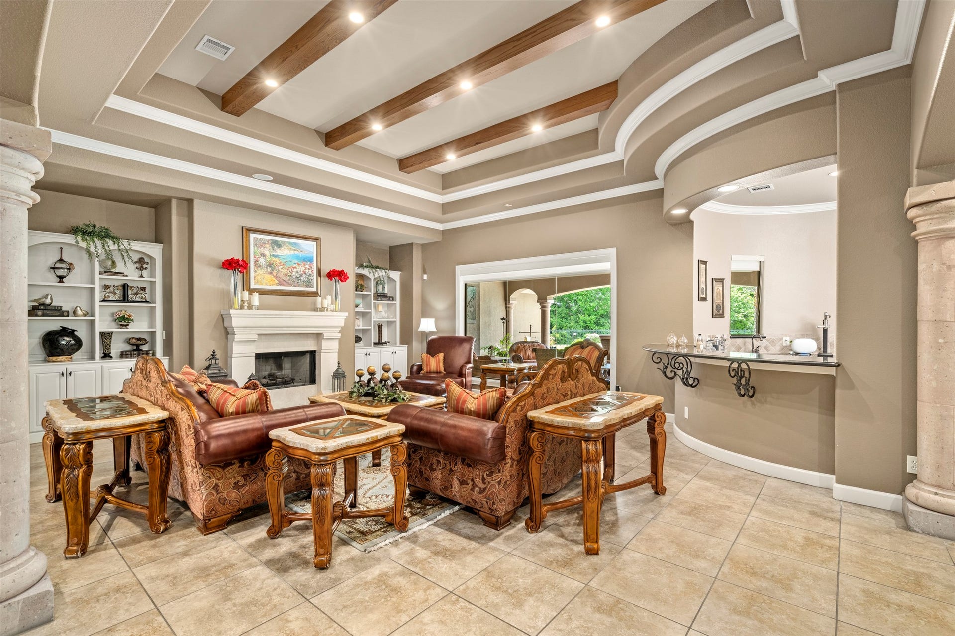 Alternate view of the formal living room highlighting the detailed double tiered tray ceilings with rich wood beams and custom built-ins.