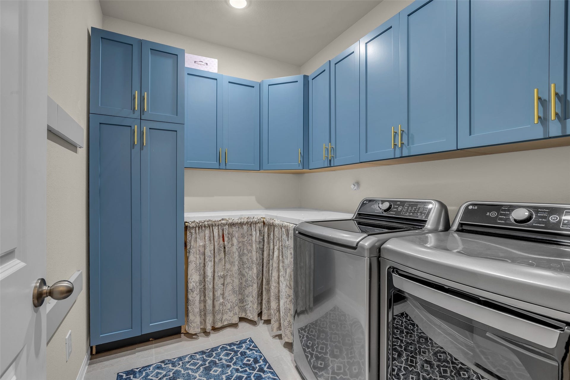 A laundry room with custom blue cabinetry and plenty of storage keeps chores organized.