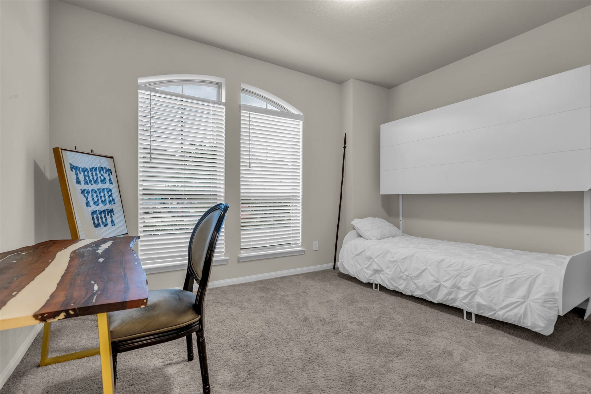 Arched windows fill this secondary bedroom with light, ideal as a guest room or home office.