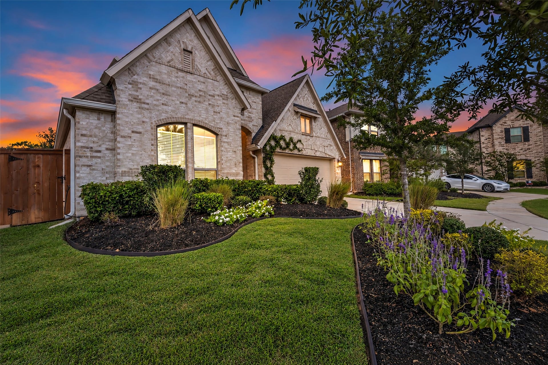 Curved garden beds and a mature tree add curb appeal from every angle.