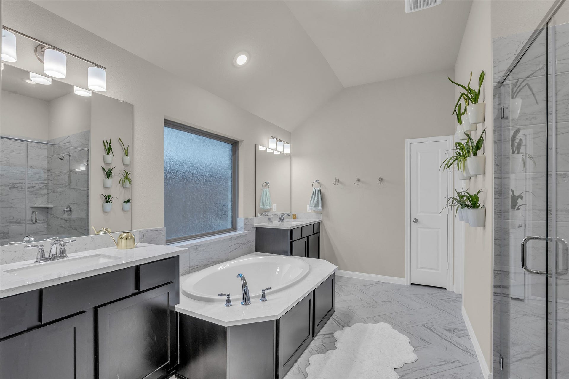 A spa-inspired primary bath featuring a soaking tub, dual vanities and frameless glass shower.