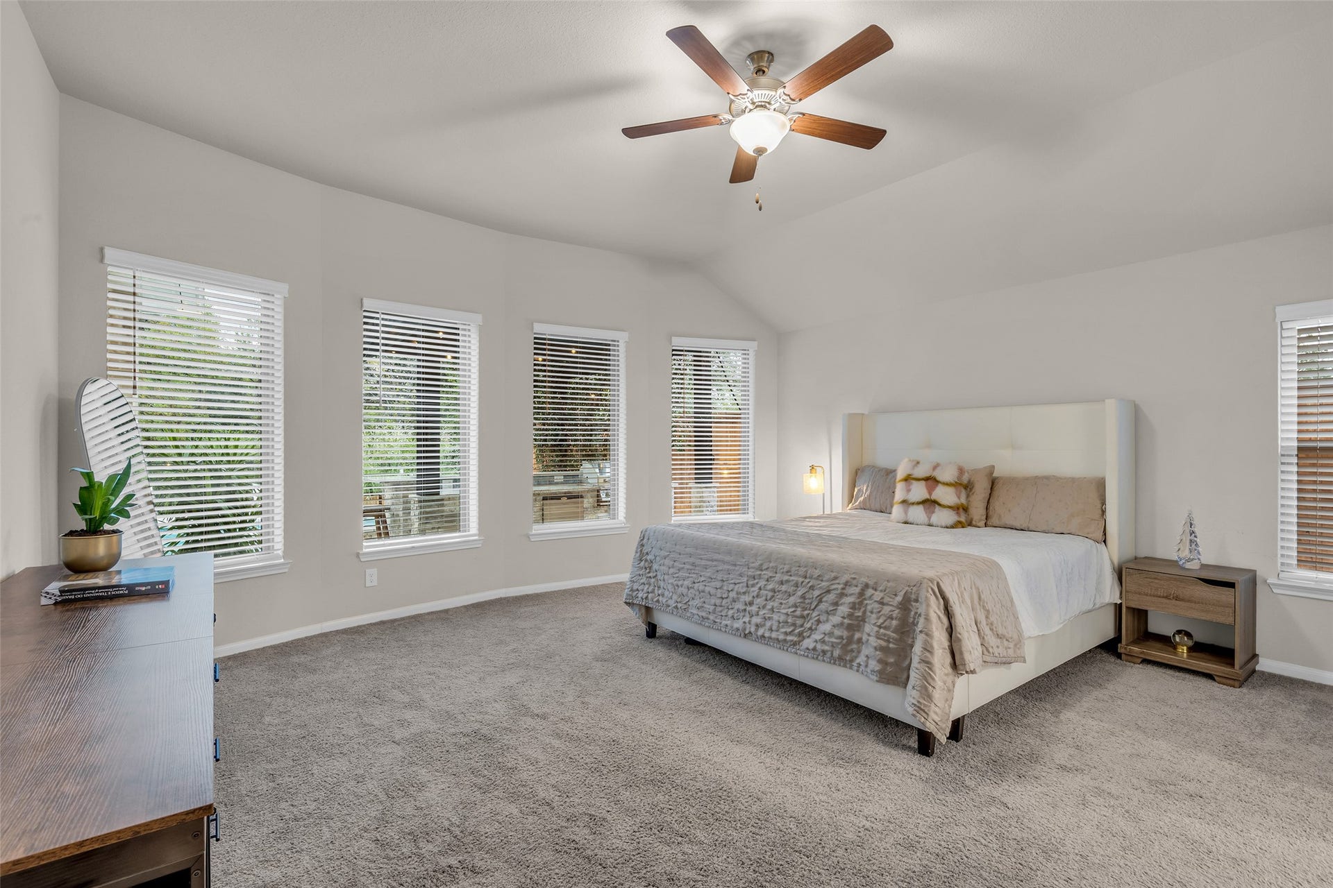 A serene primary retreat featuring vaulted ceilings and a beautiful bay of windows.