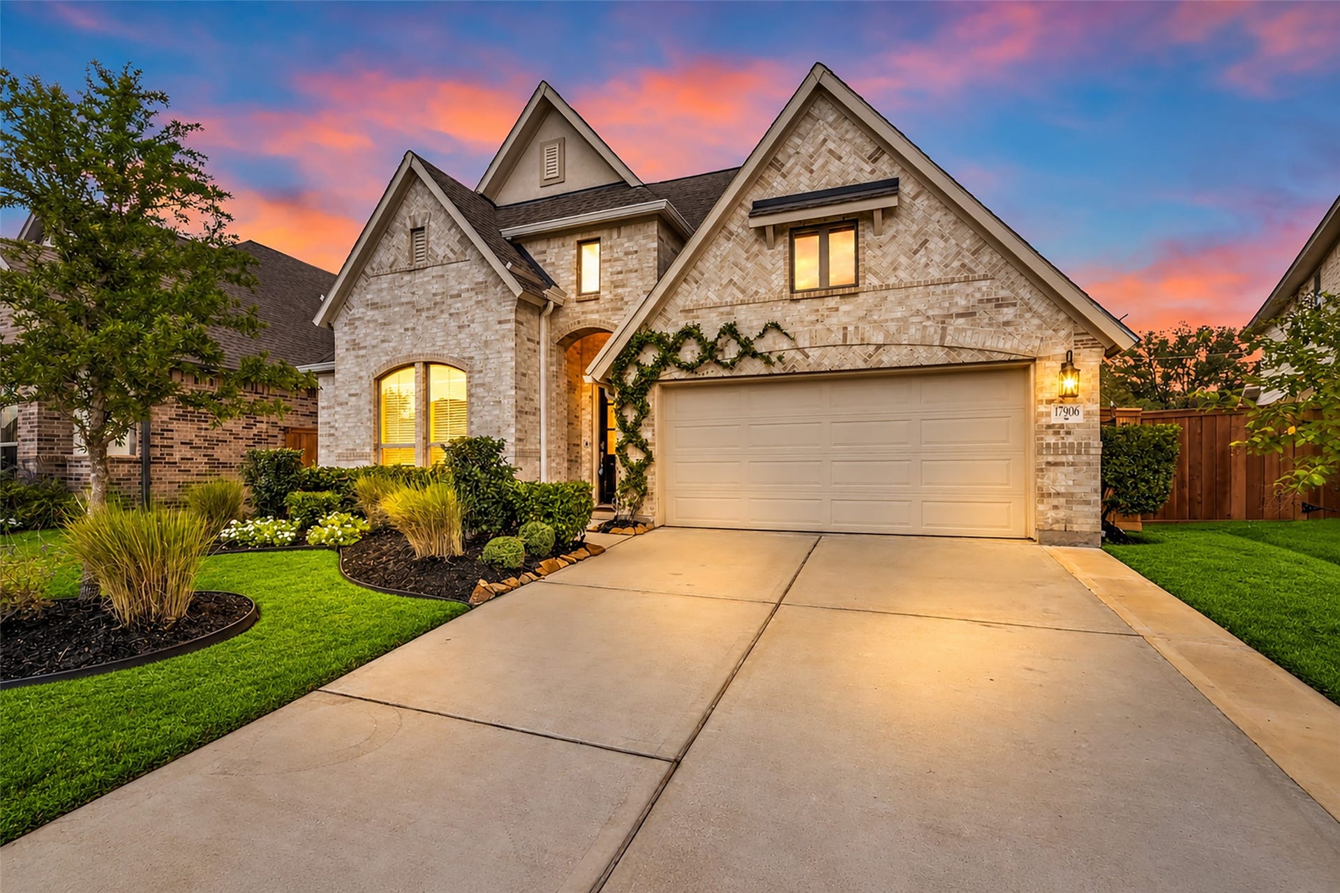 Beautiful architecture and lush landscaping create captivating curb appeal at twilight.